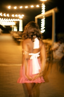 Woman in pink dress walking at night with lights