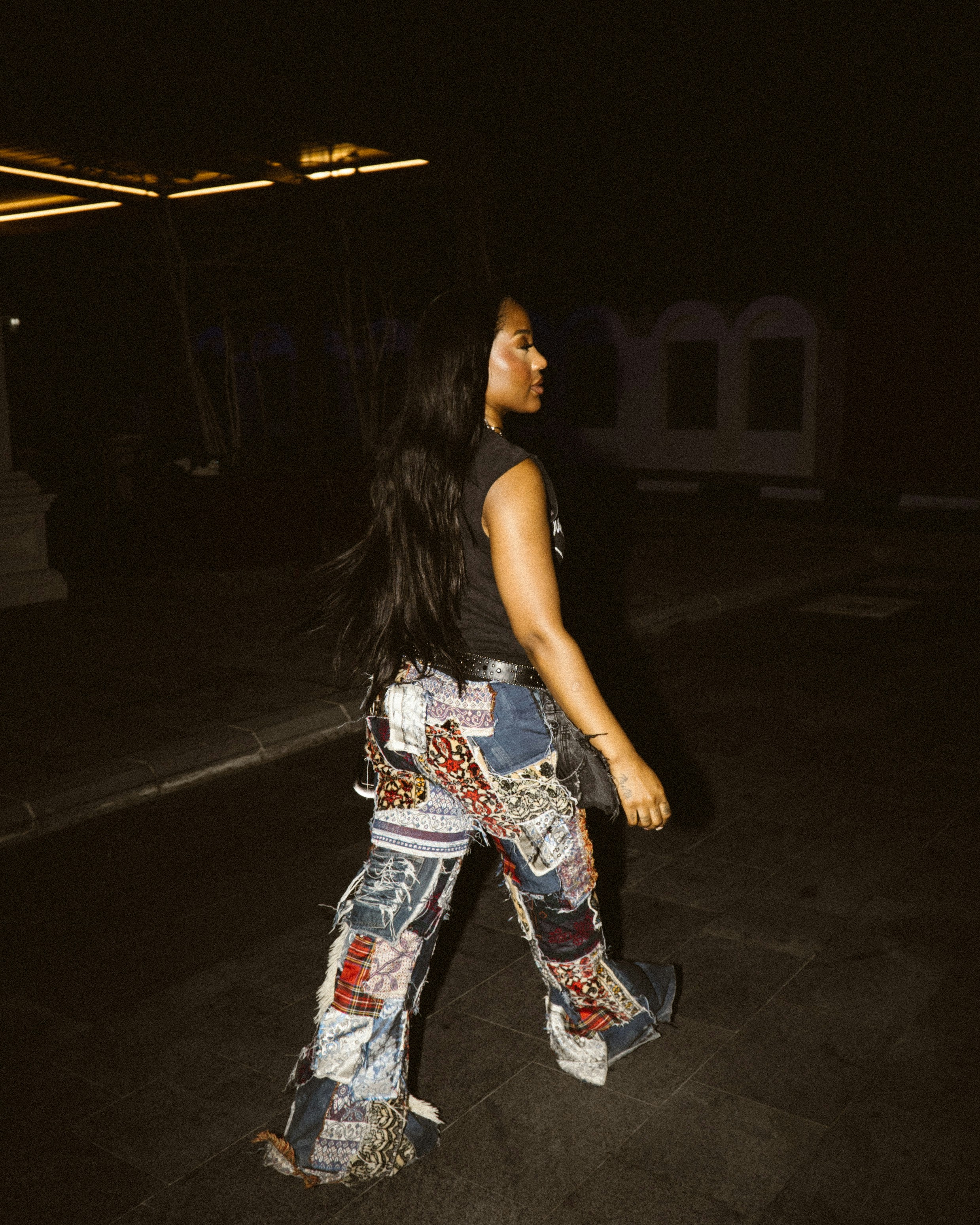 Donna che cammina di notte in jeans patchwork