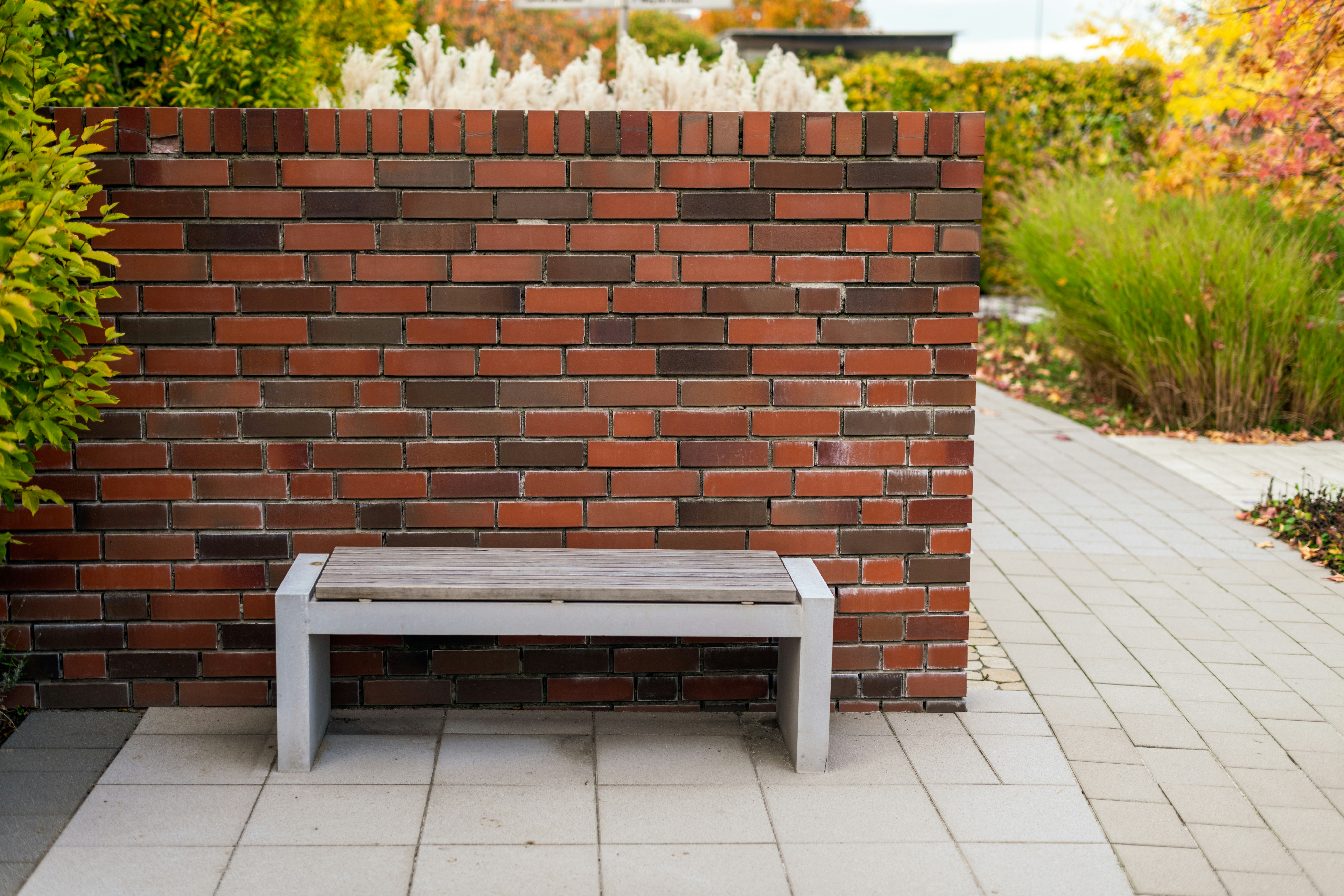 A modern bench against a brick wall in a garden.