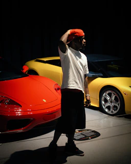 Man poses with red and yellow sports cars