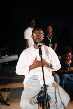 Man singing into microphone with hands on chest.