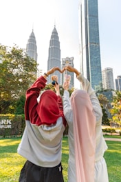 Two people making heart shapes with hands in park