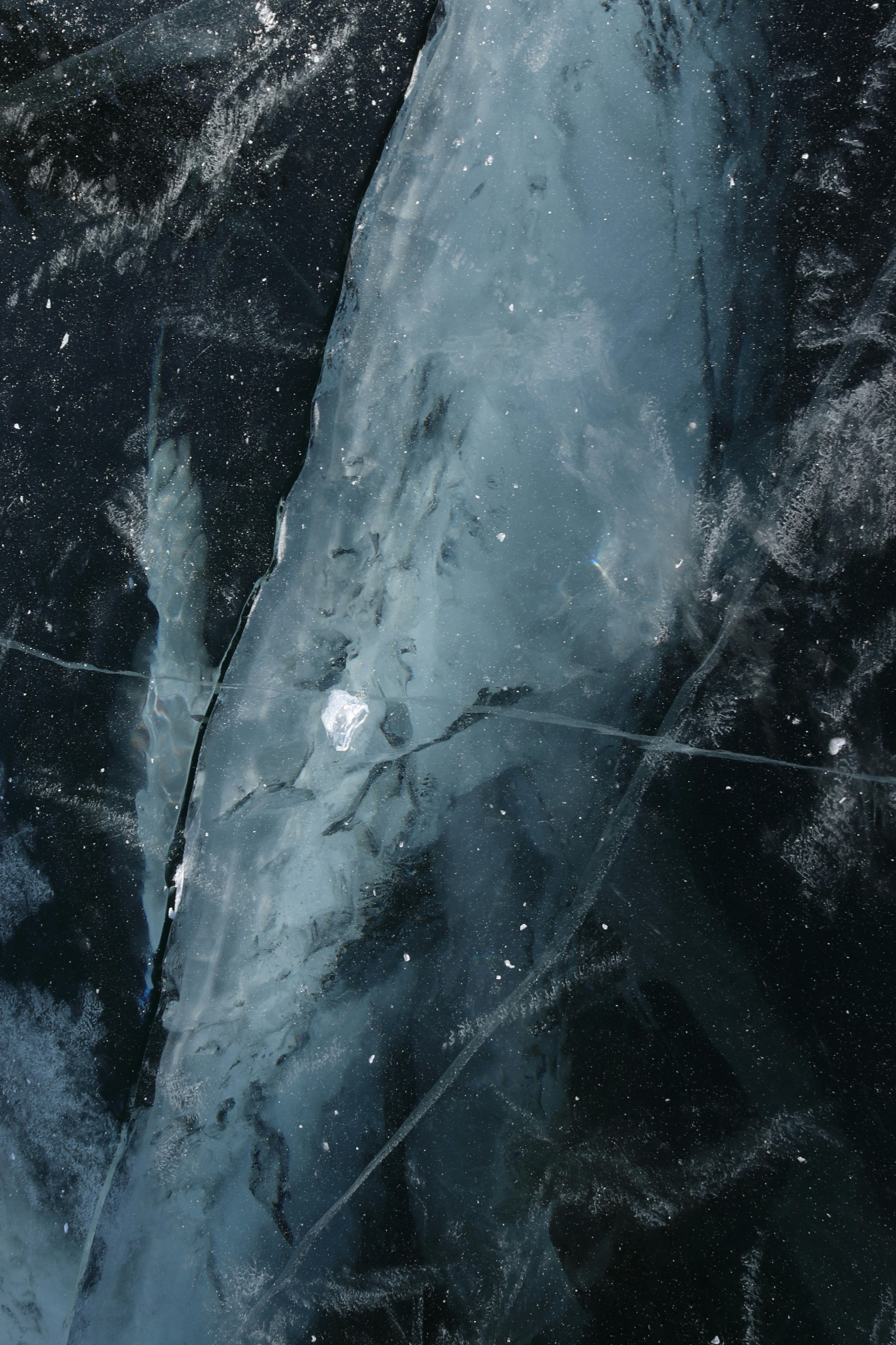 Close-up of cracked blue ice with dark background