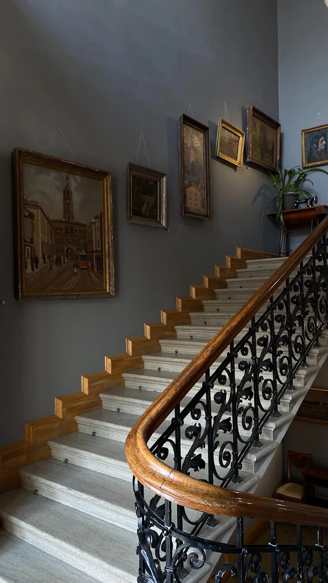 Marble staircase with a black wrought-iron railing and wooden handrail