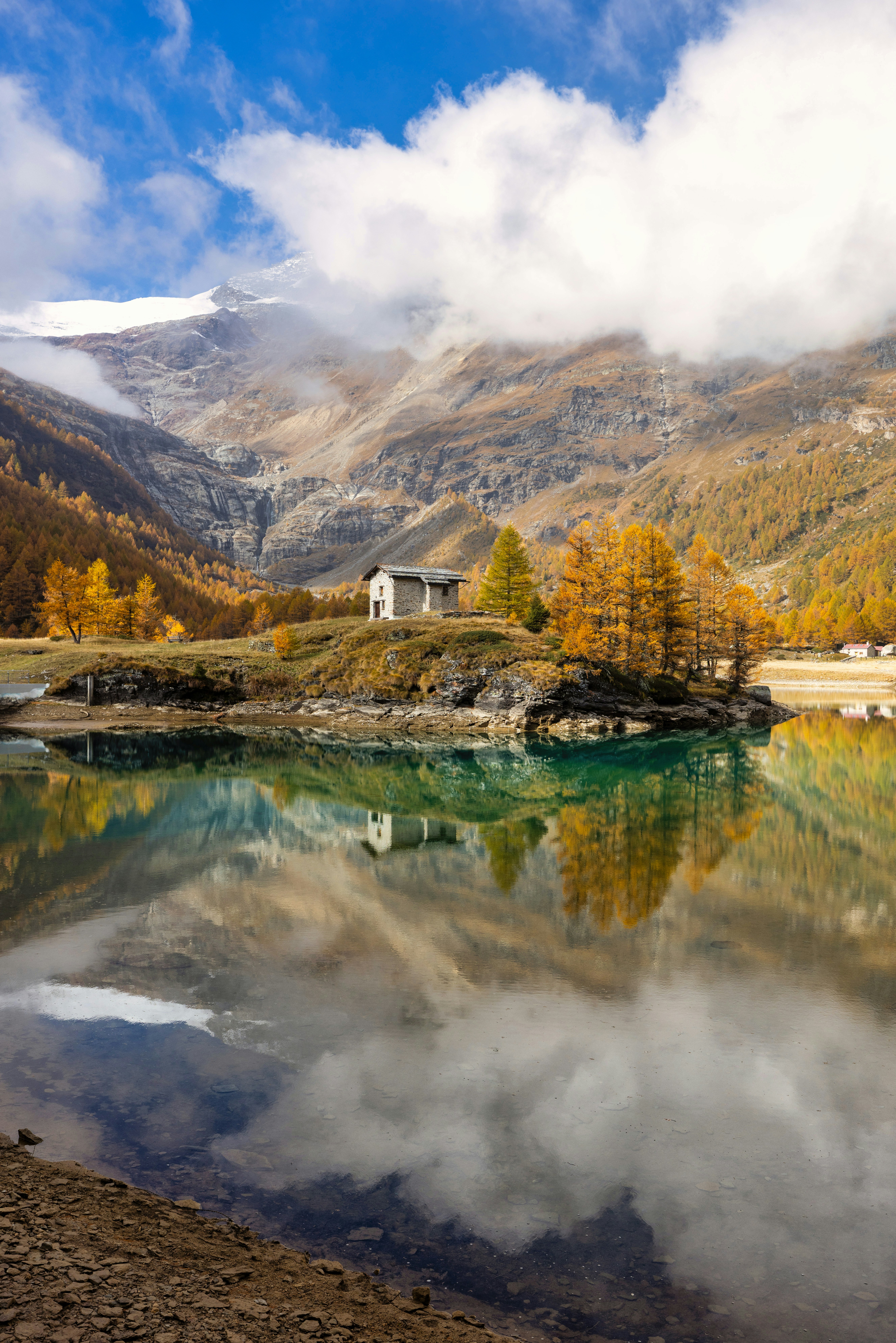 Petite maison sur l’île avec des arbres d’automne se reflétant dans le lac.
