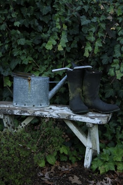 Watering can and boots on a rustic bench