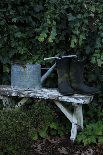 Watering can and boots on a rustic bench