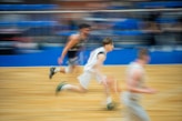 Basketball players running on wooden court