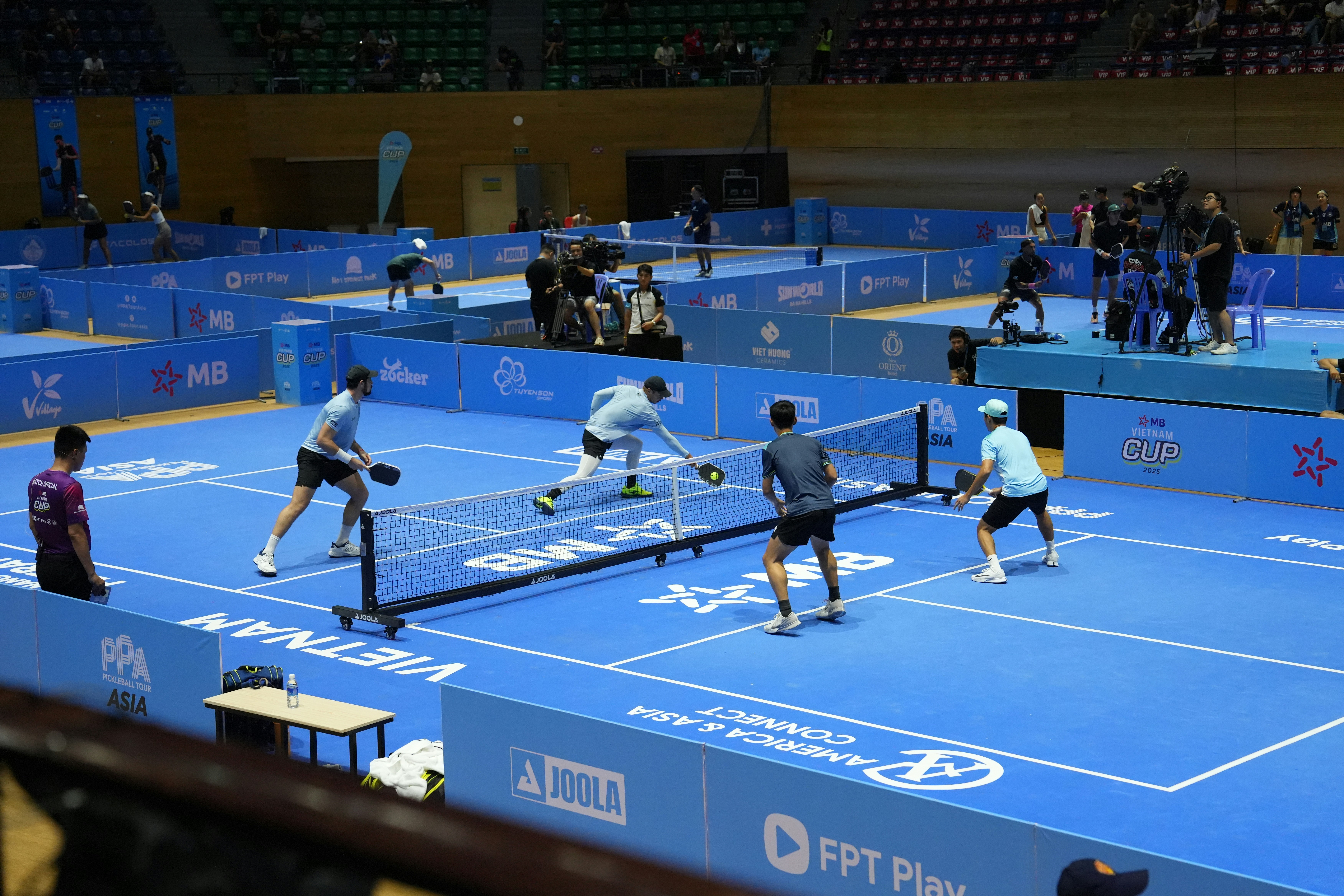 Players compete in a pickleball match on a blue court.