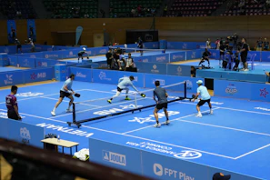 Players compete in a pickleball match on a blue court.