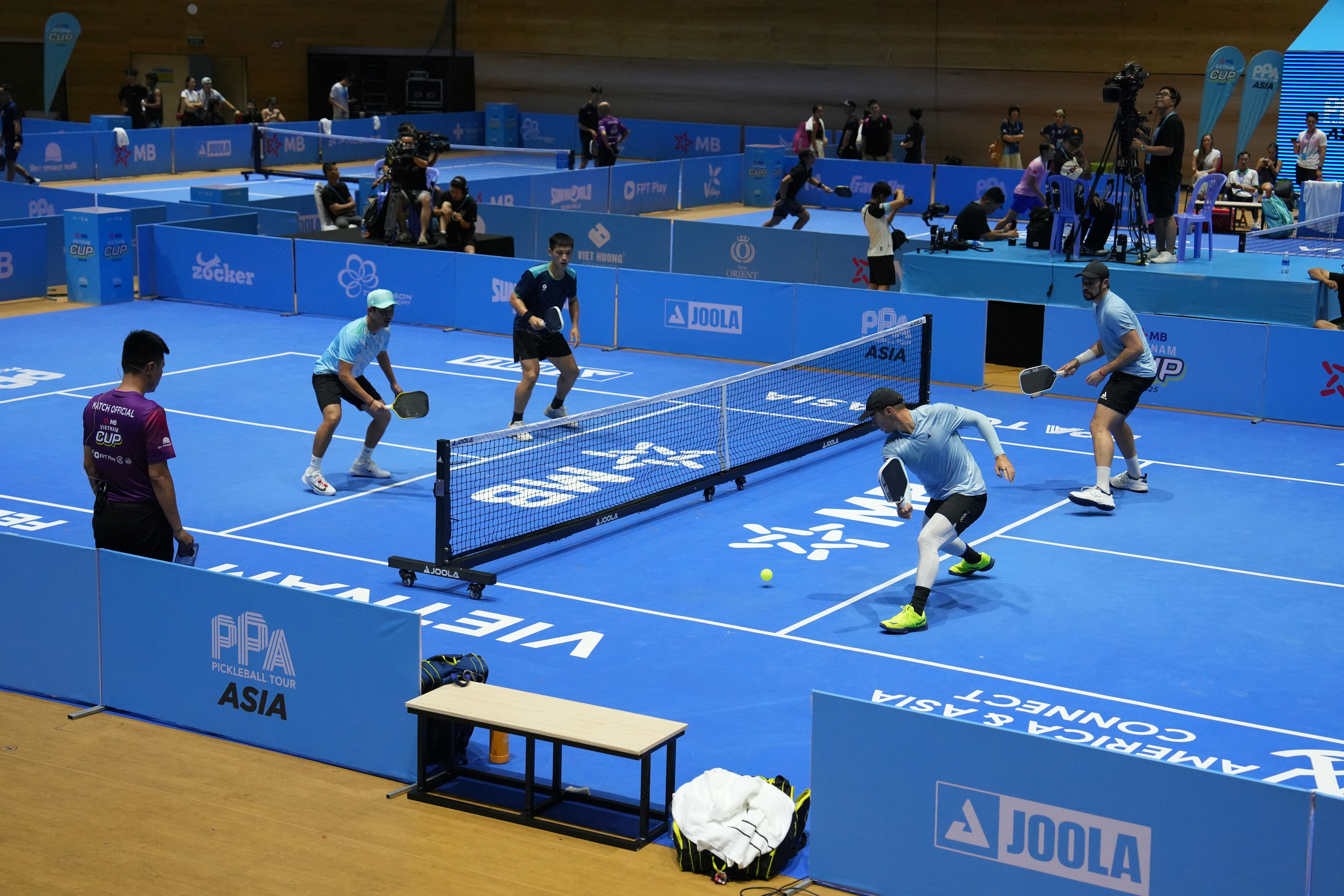 Players compete in a pickleball match on a blue court.