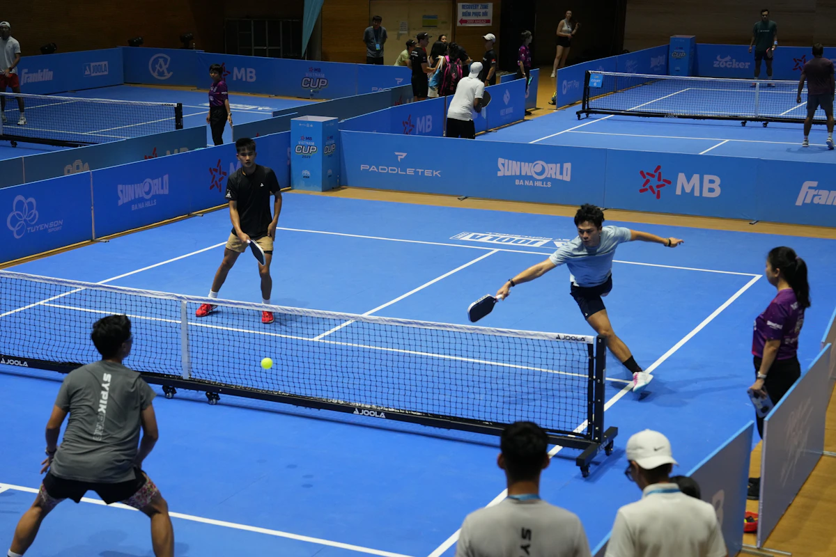 Players competing in a pickleball match on blue courts
