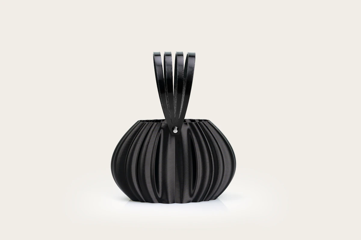 Sculptural black pleated sling bag on a pale backdrop