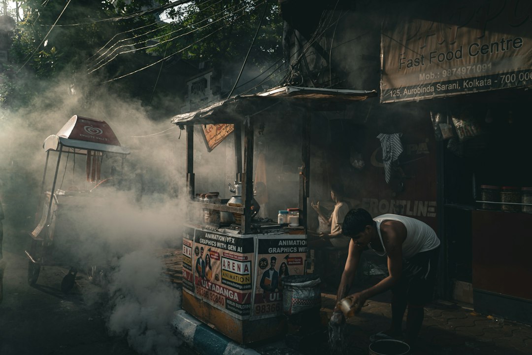 Street vendor preparing food amidst smoke and steam.