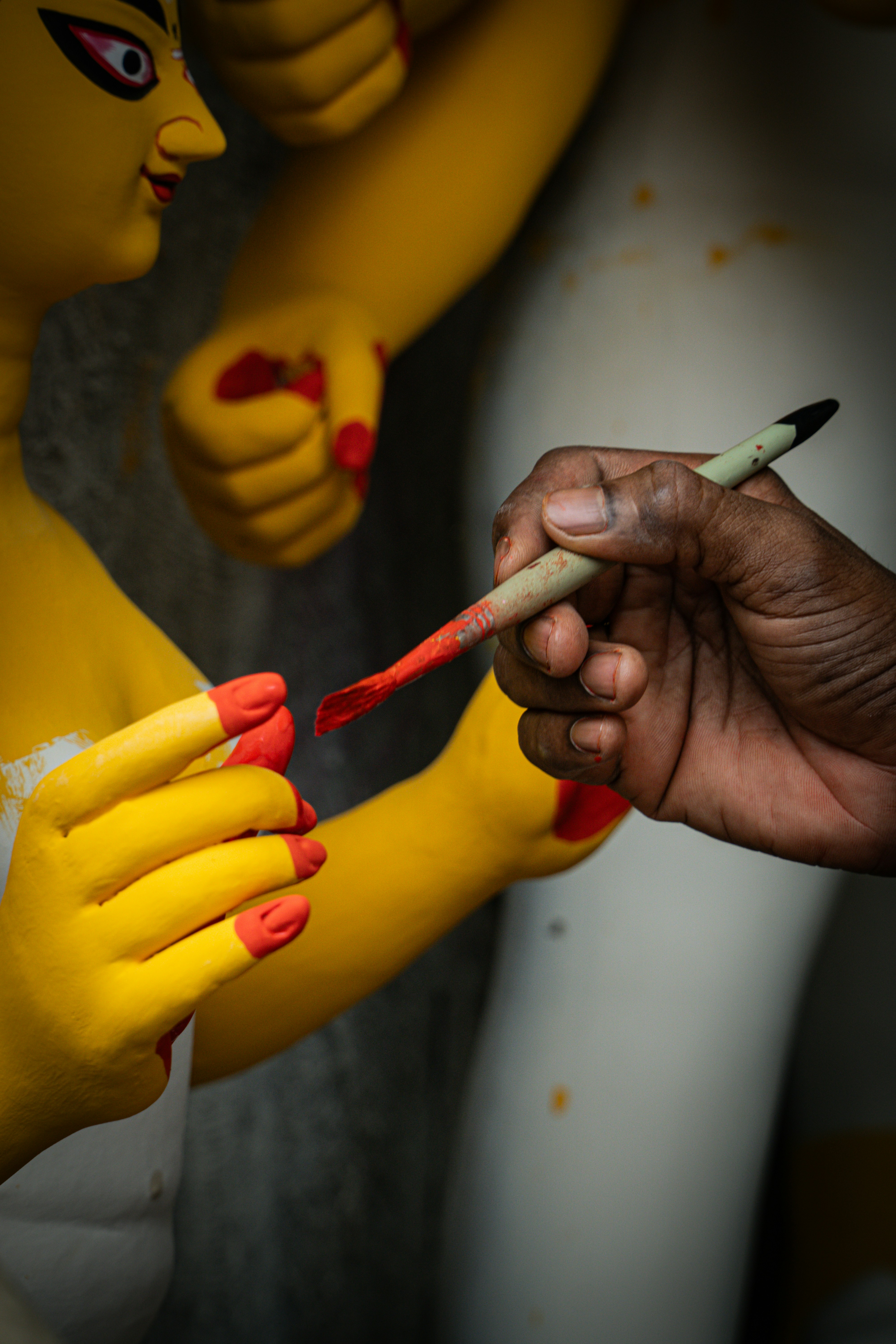 Artist painting a sculpture's hands red fingernails
