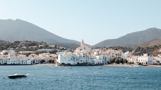 White buildings on the coast with mountains behind.