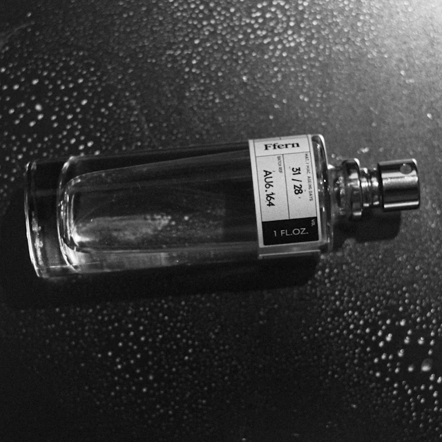 A clear glass perfume bottle with a silver cap