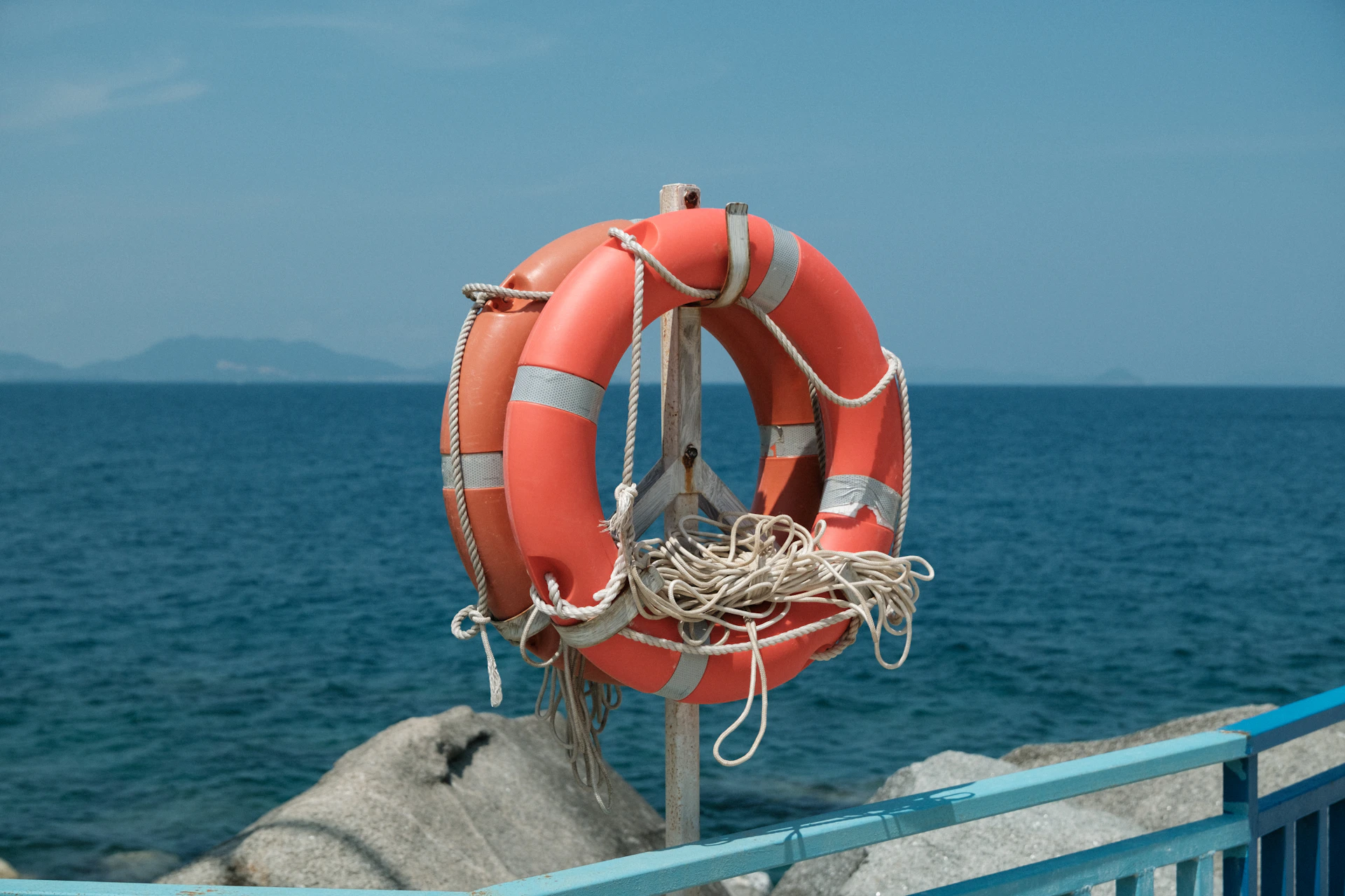 Two orange life preservers on a post by the sea
