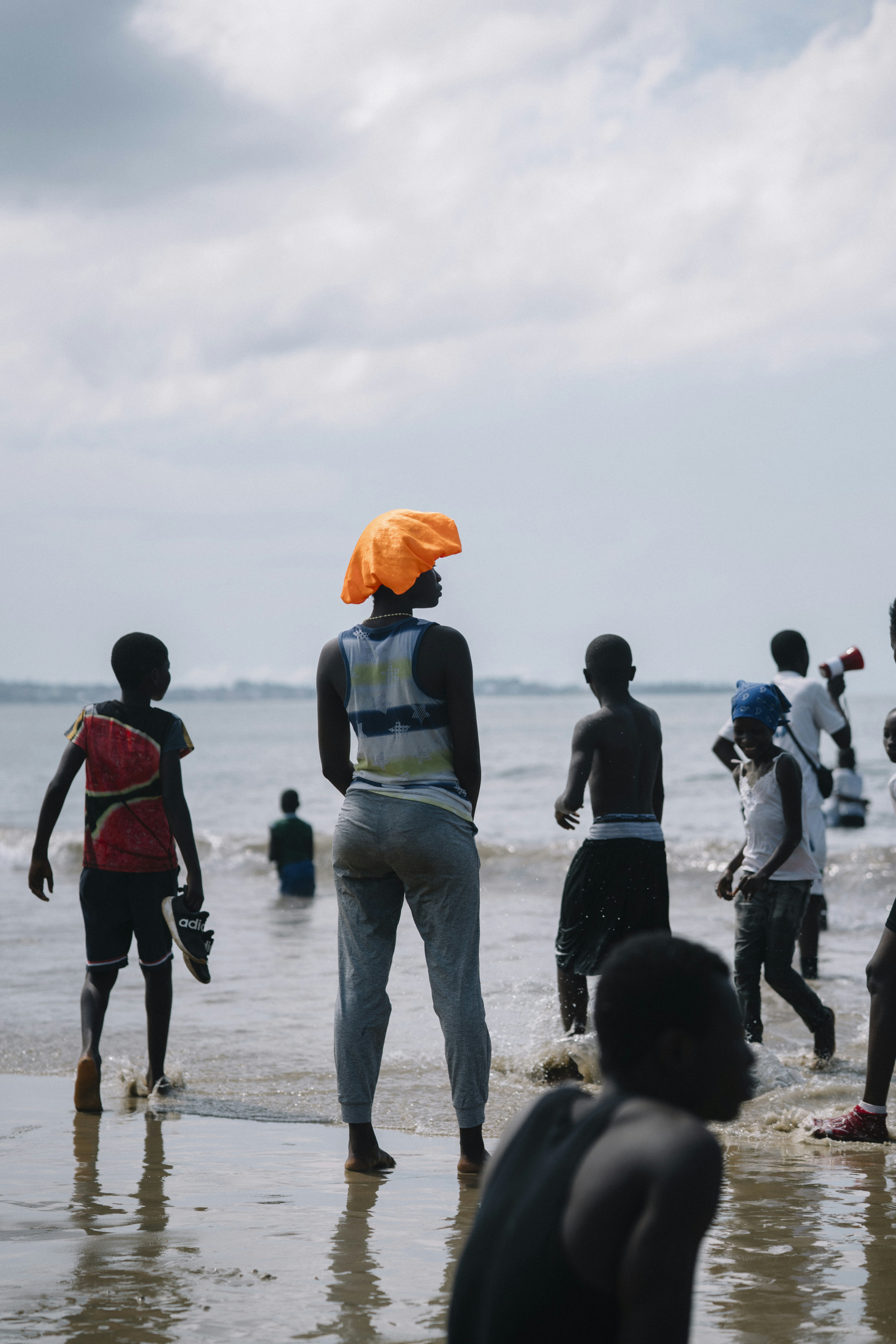 People wading in the ocean under a cloudy sky