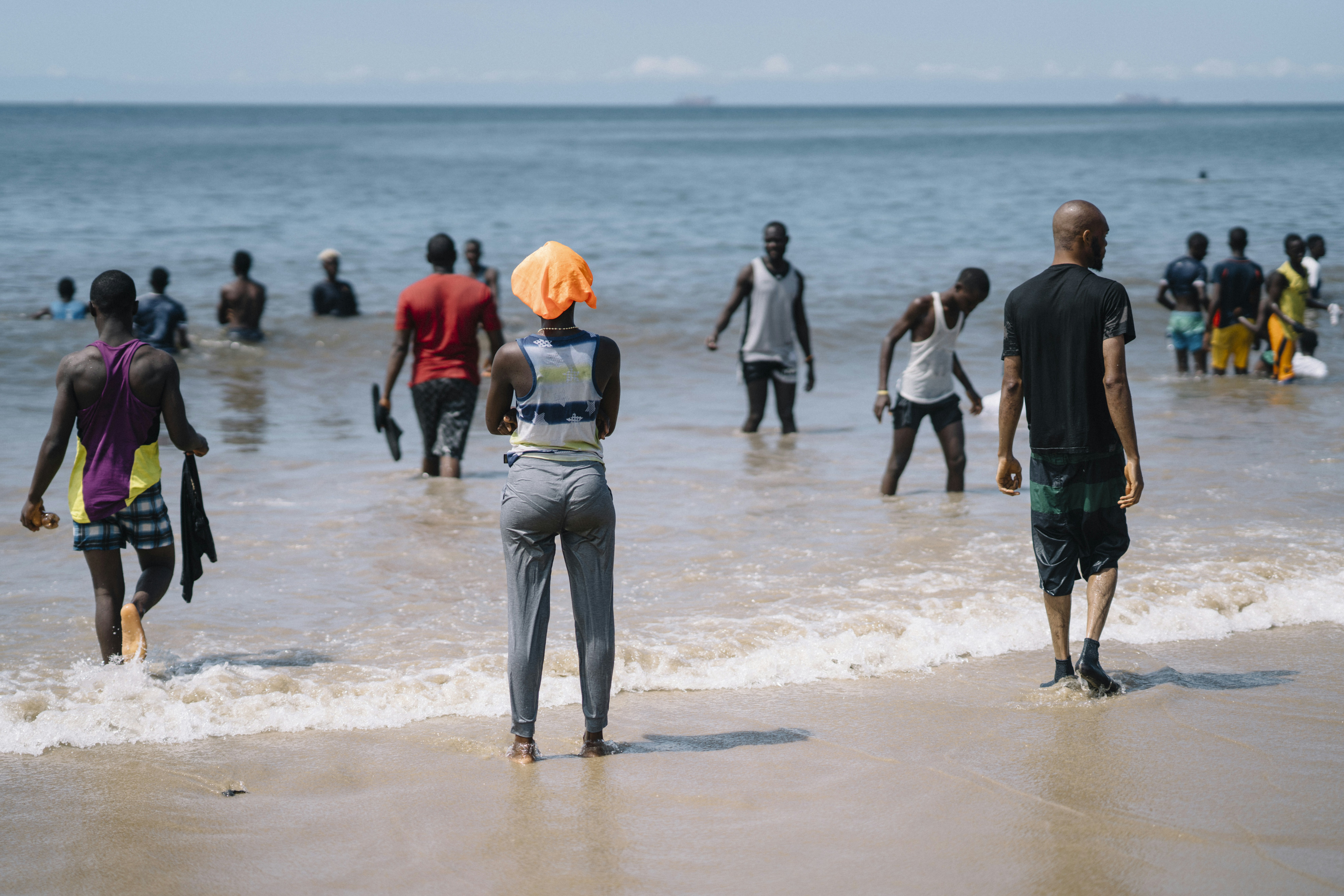 People wading into the ocean on a sunny day.