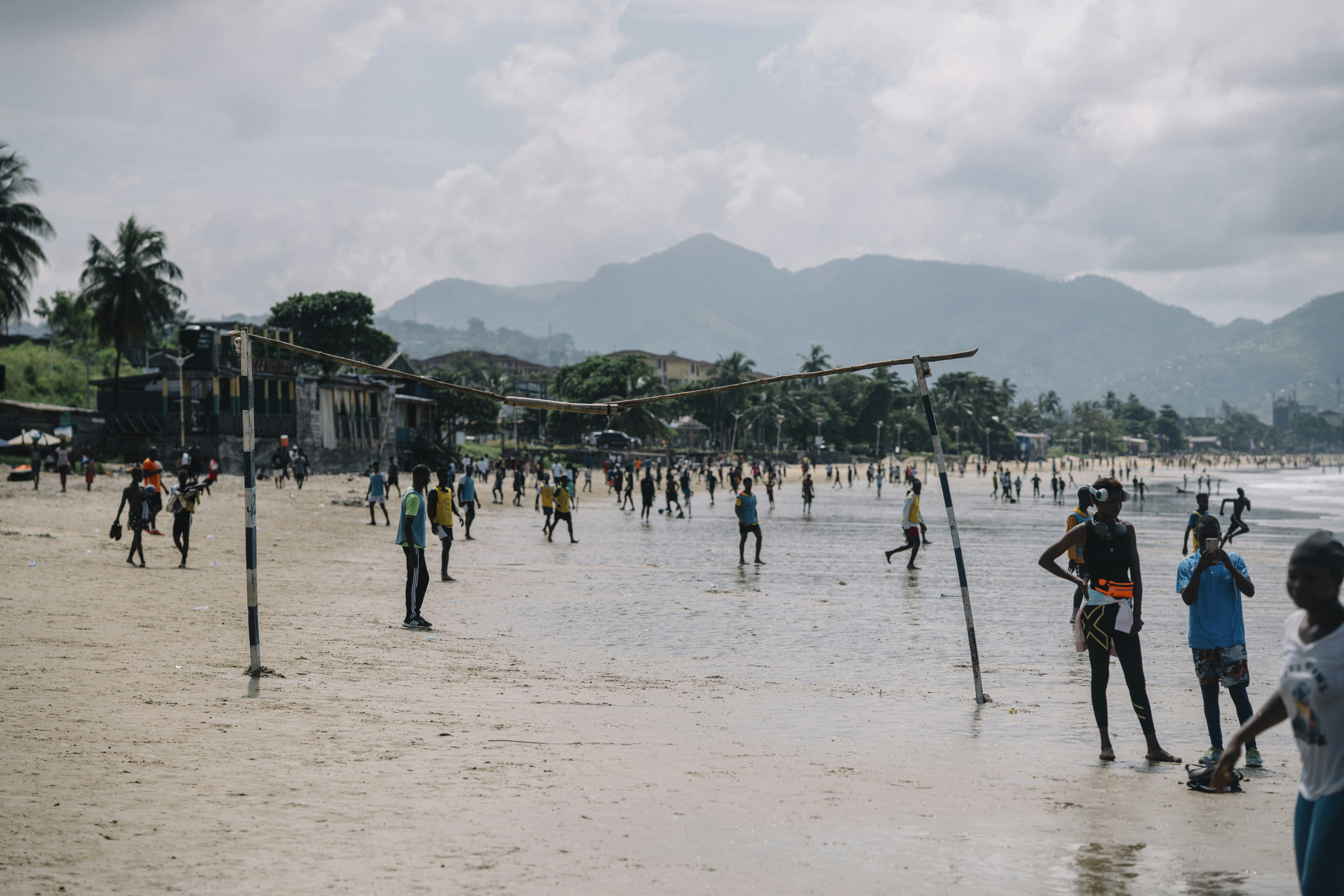People playing soccer on a tropical beach.