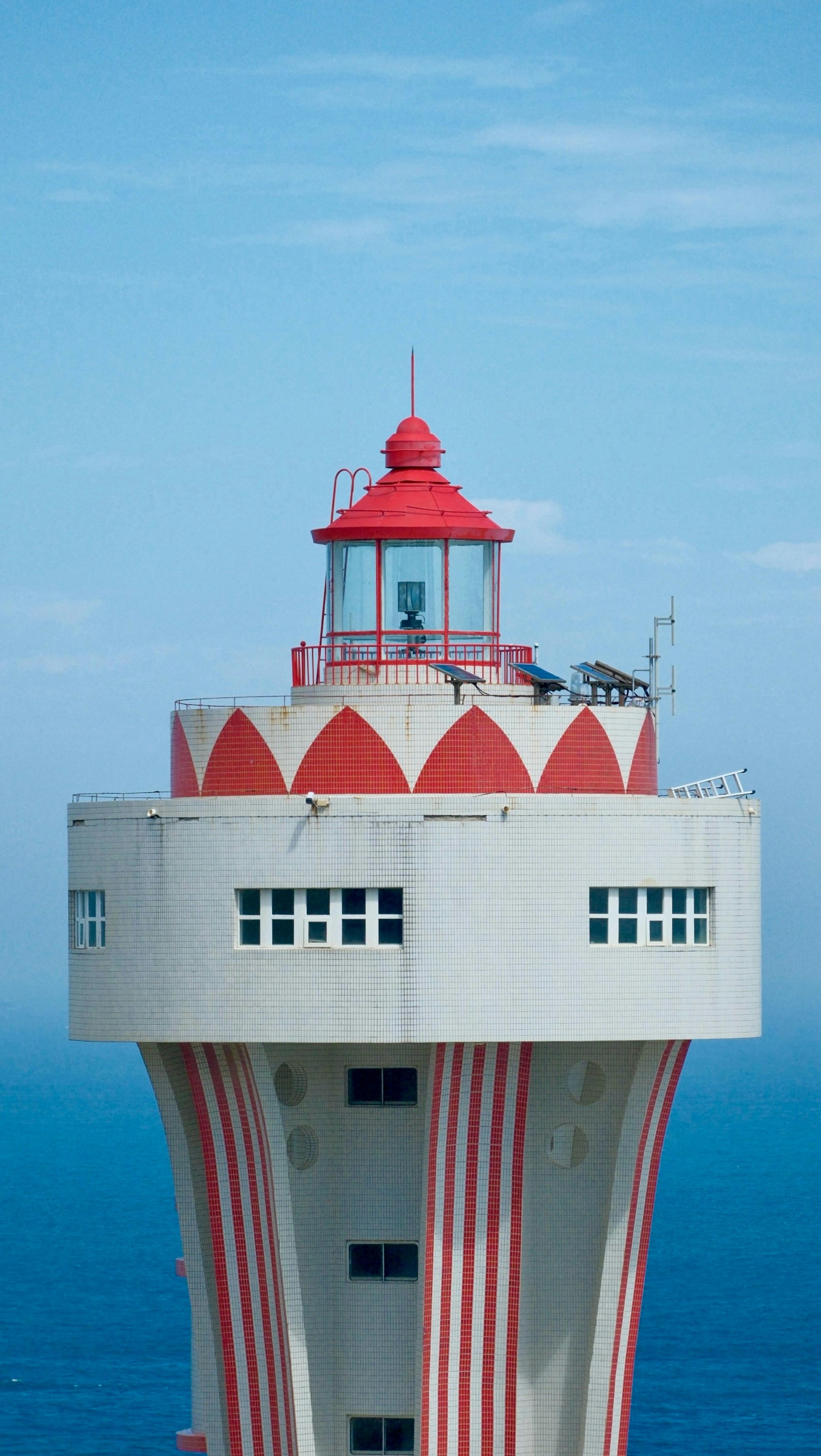 Ein hoher Leuchtturm mit rot-weißen Streifen.