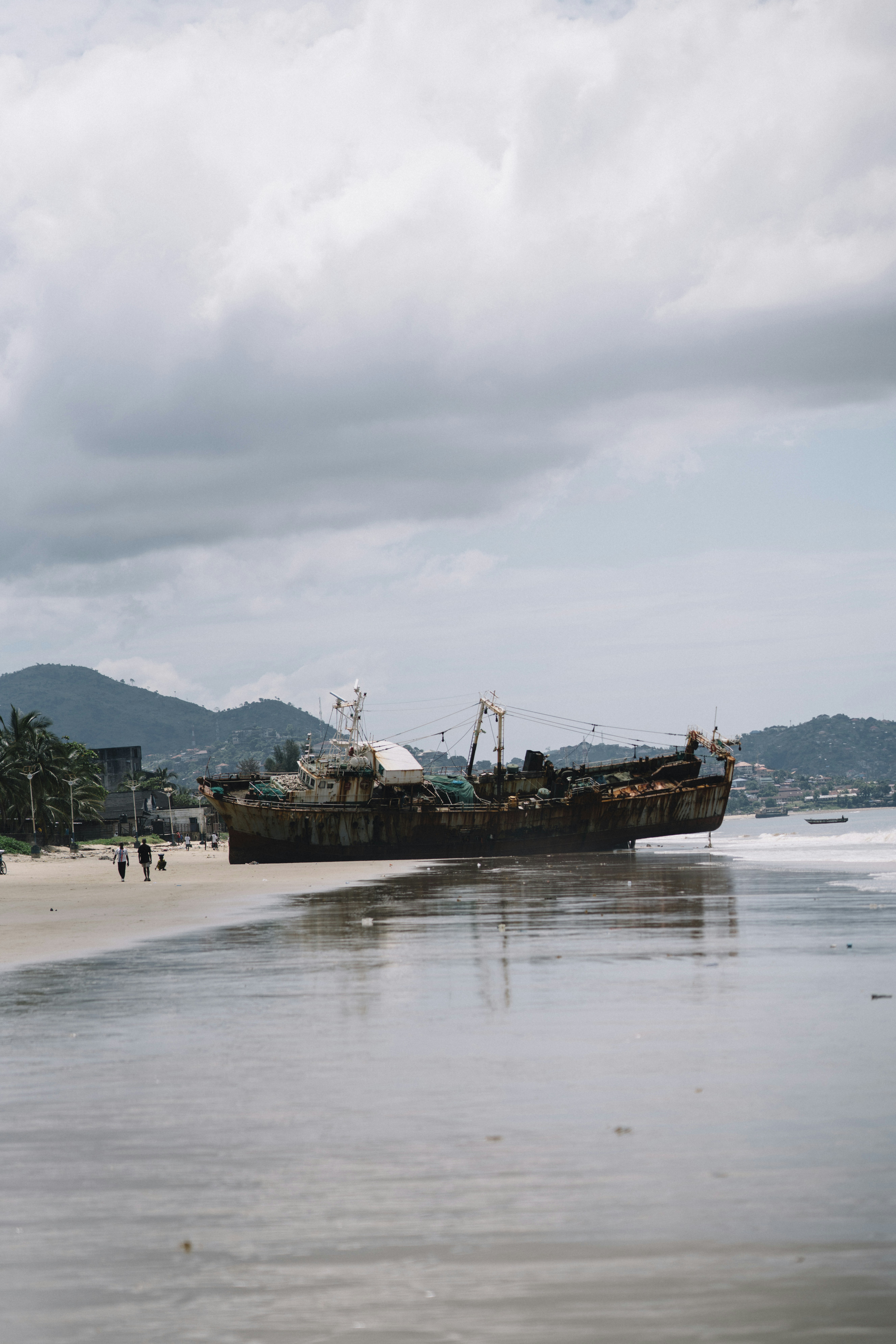 Old shipwreck resting on a sandy beach shore.