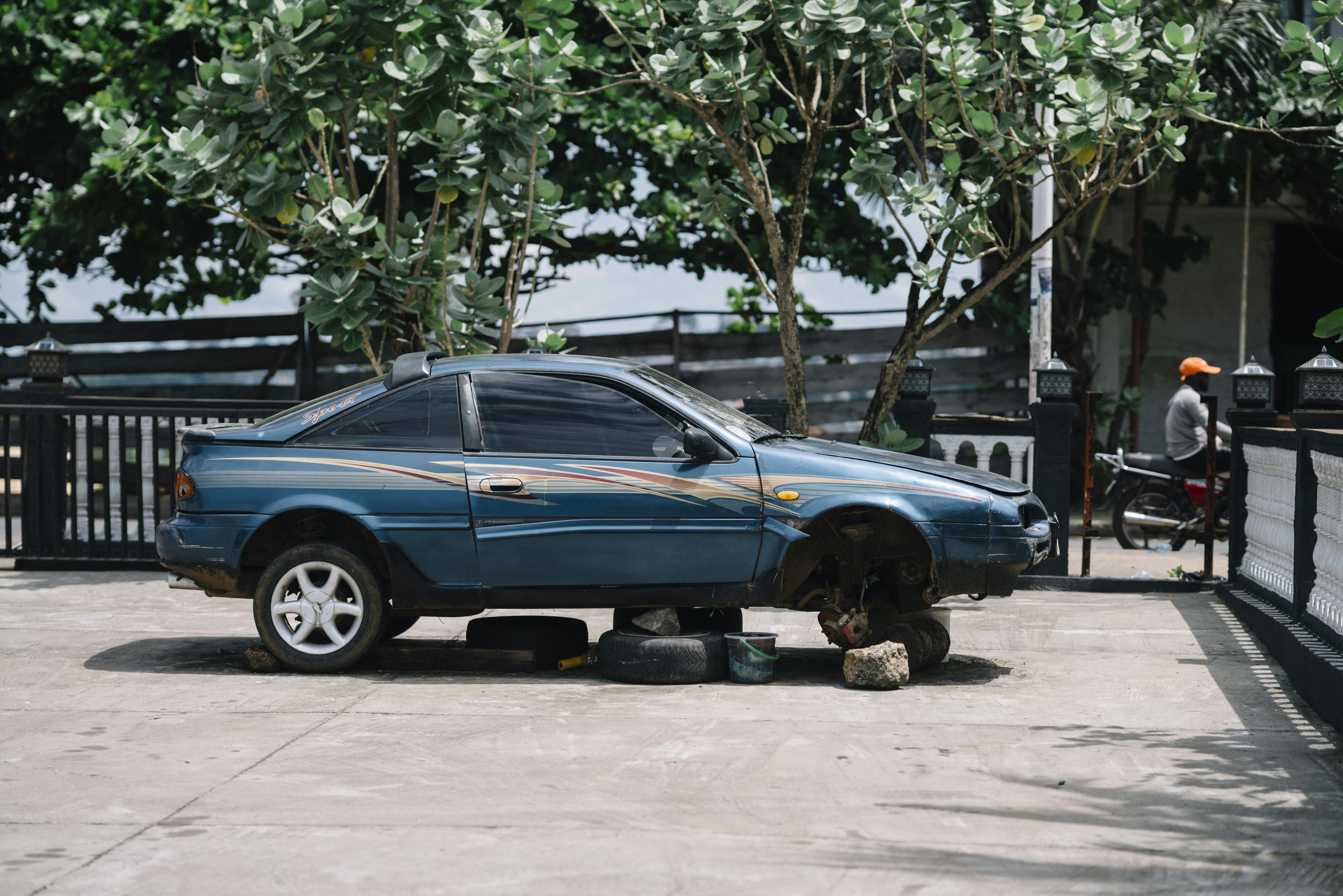 Blaues Auto mit abgenommenen Rädern sitzt auf Blöcken