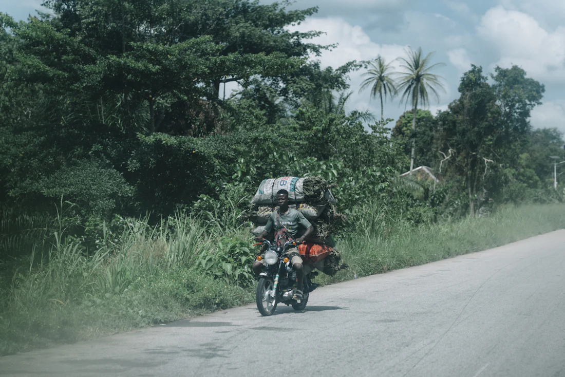Conducteur de deux-roues transportant passagers et marchandises sur une route.
