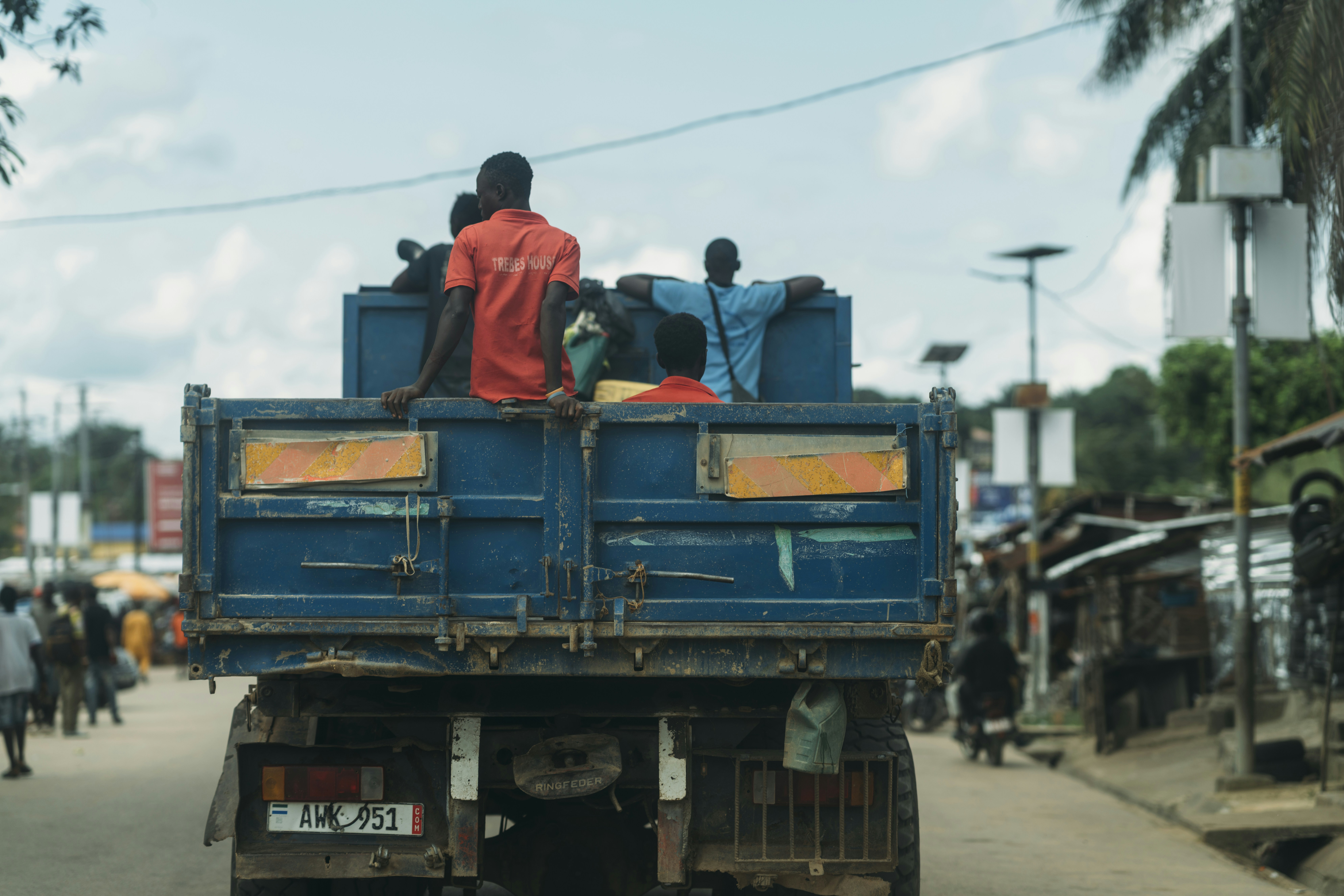 People ride in the back of a blue truck.