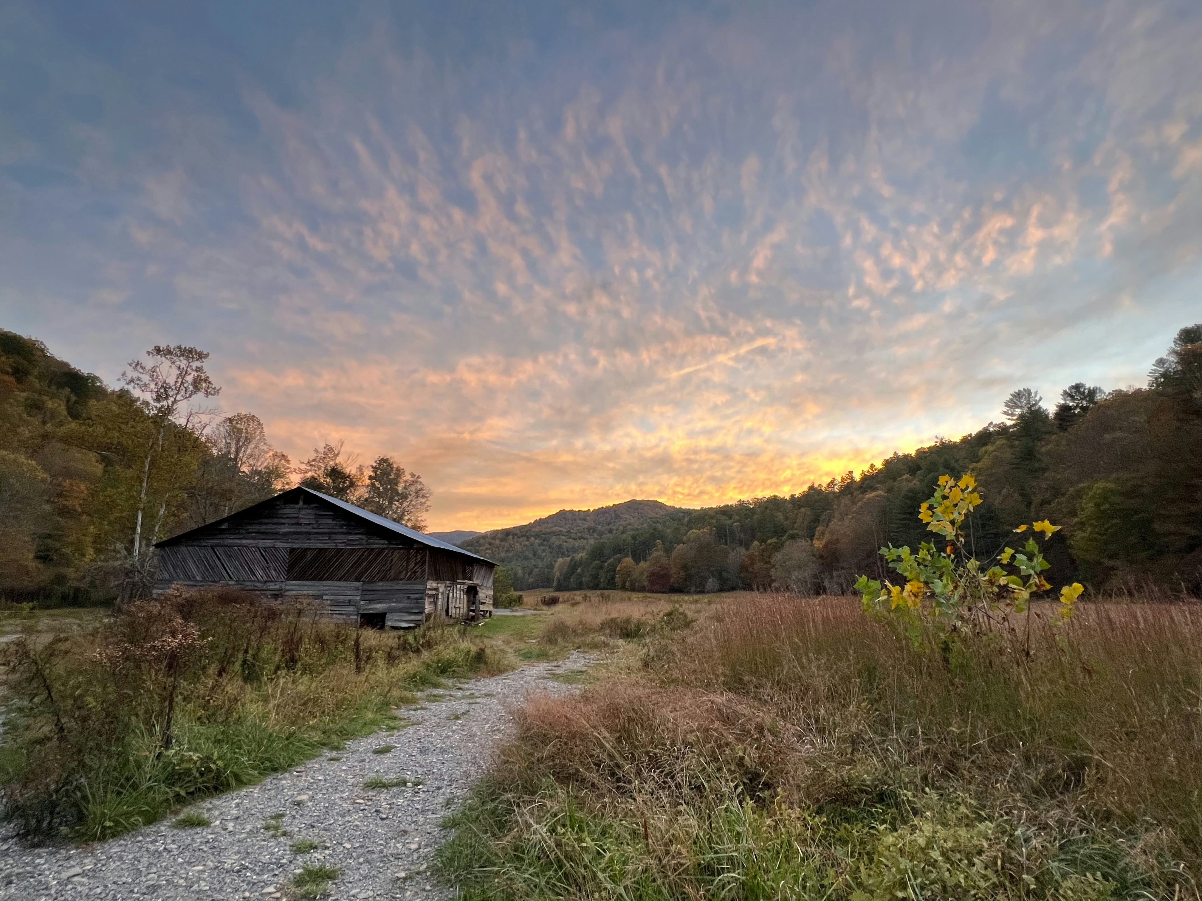 Old barn in a field at sunrise with colorful sky