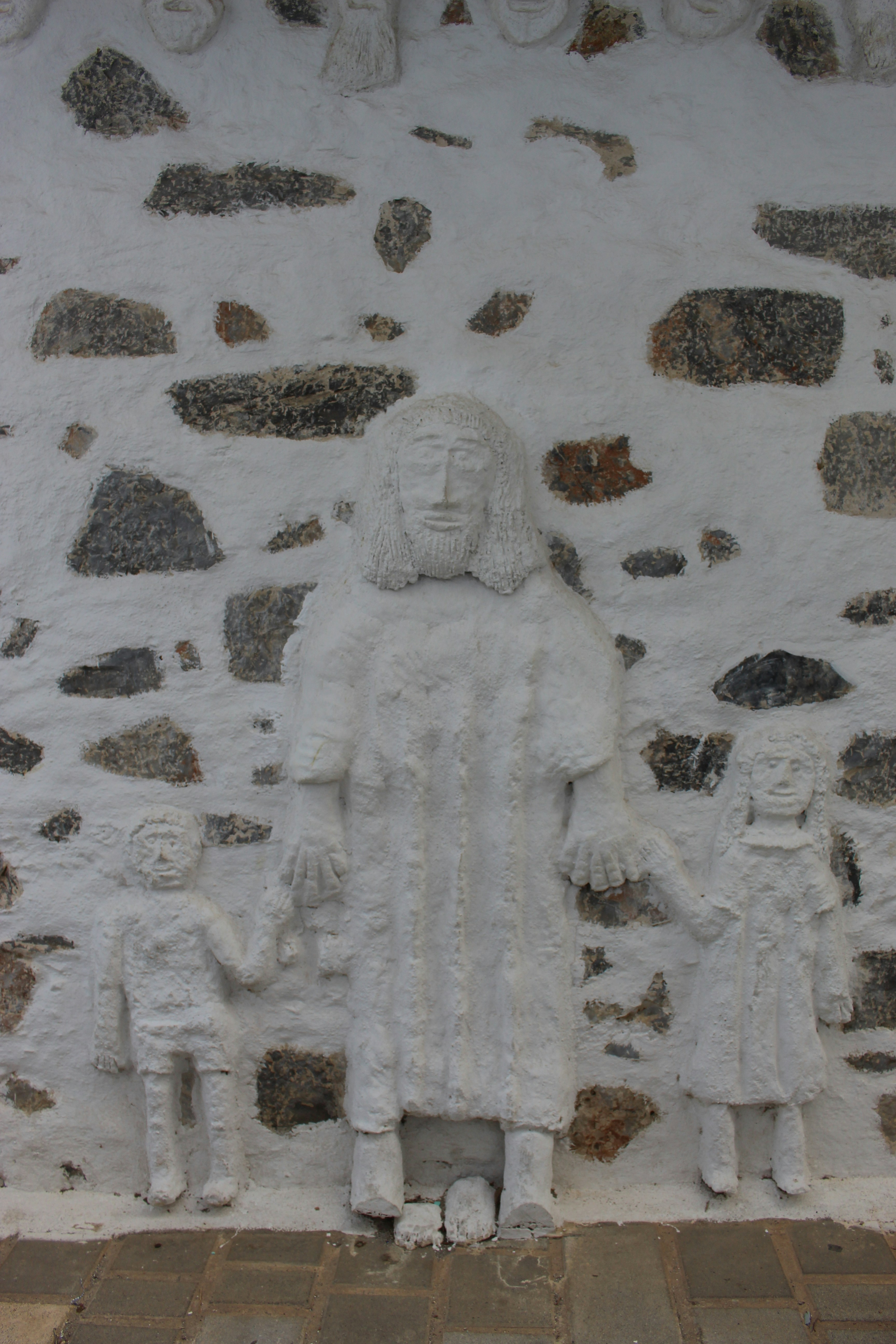 White relief sculpture of a family on stone wall.