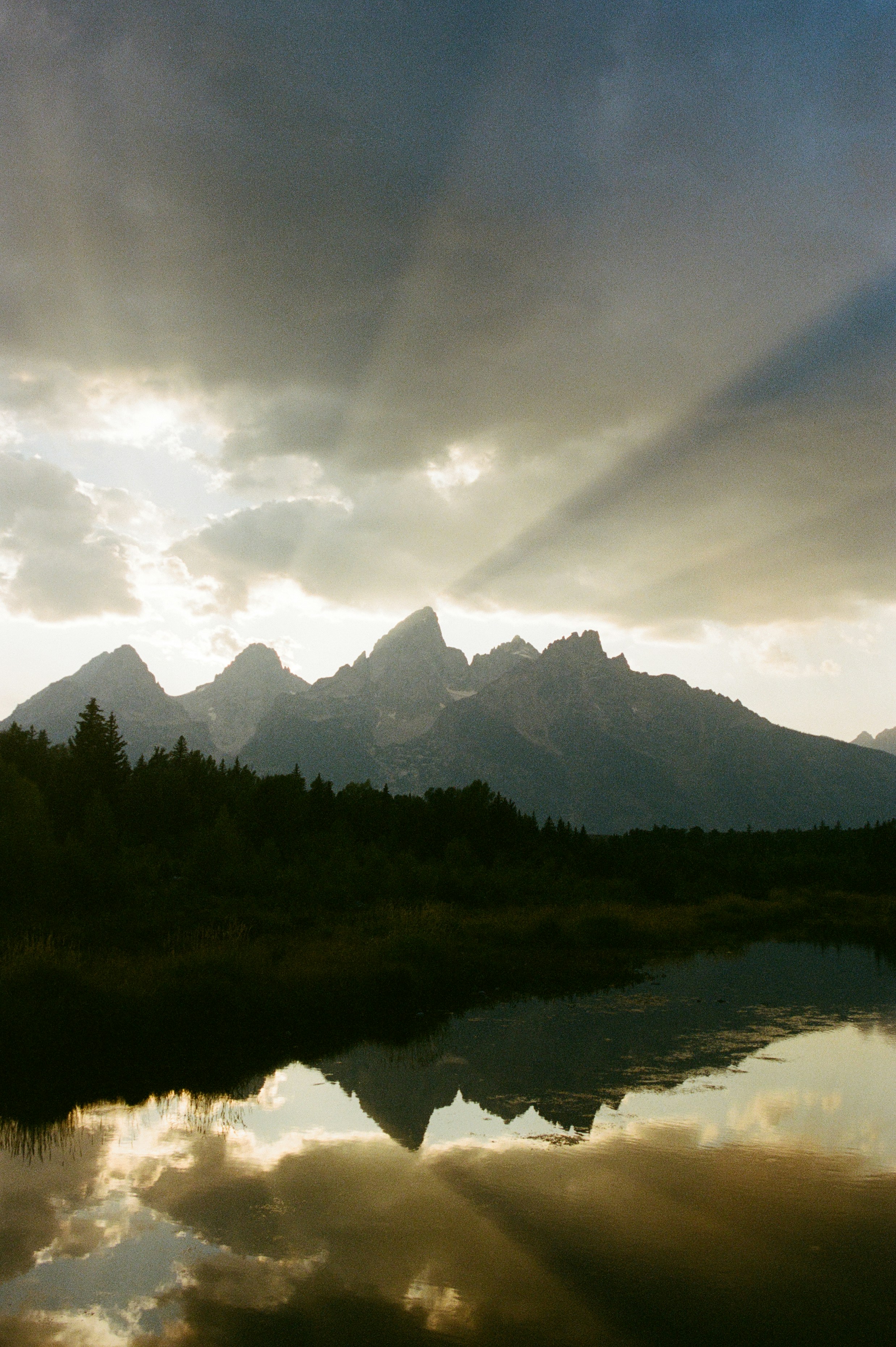 Sunbeams through clouds over mountain reflection