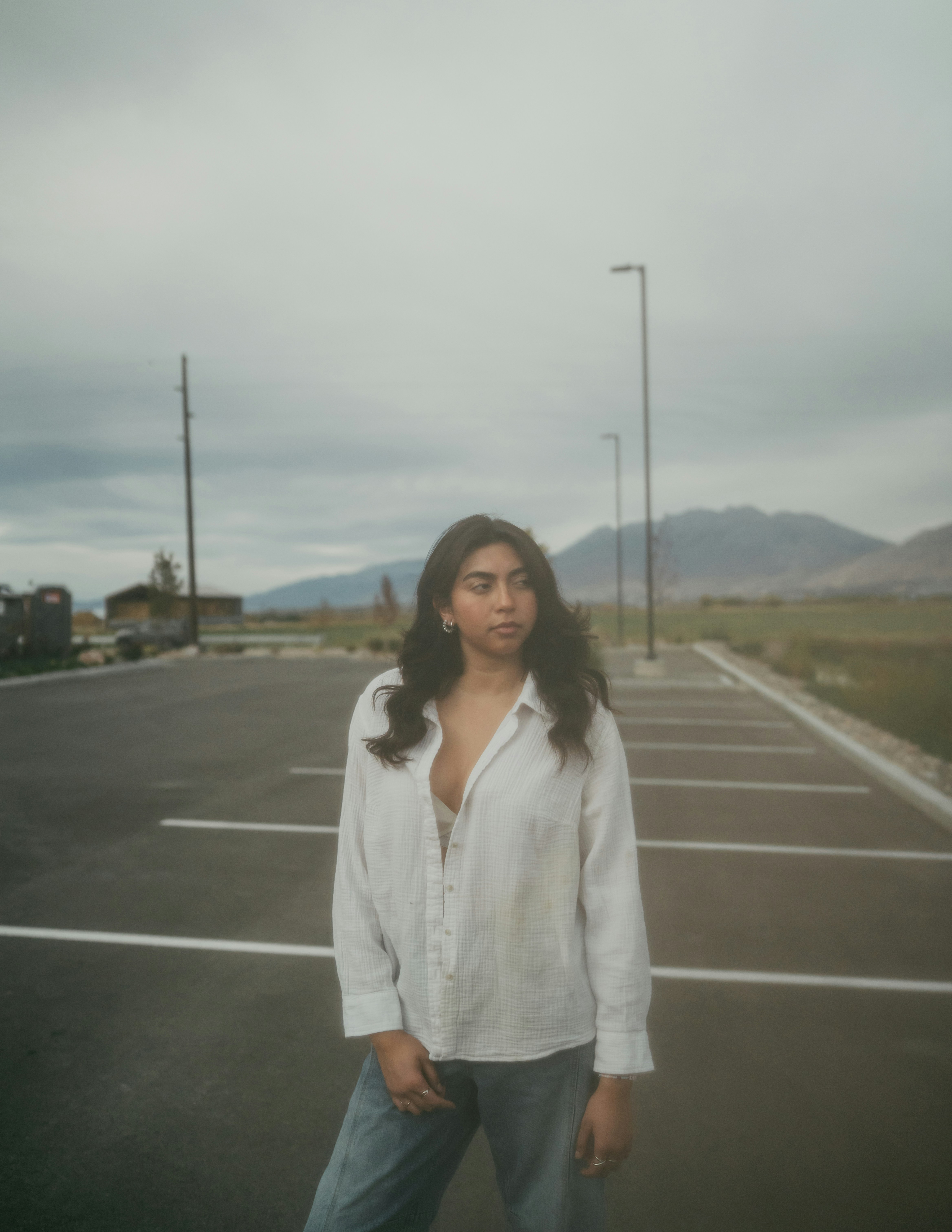 A woman stands in an empty parking lot.