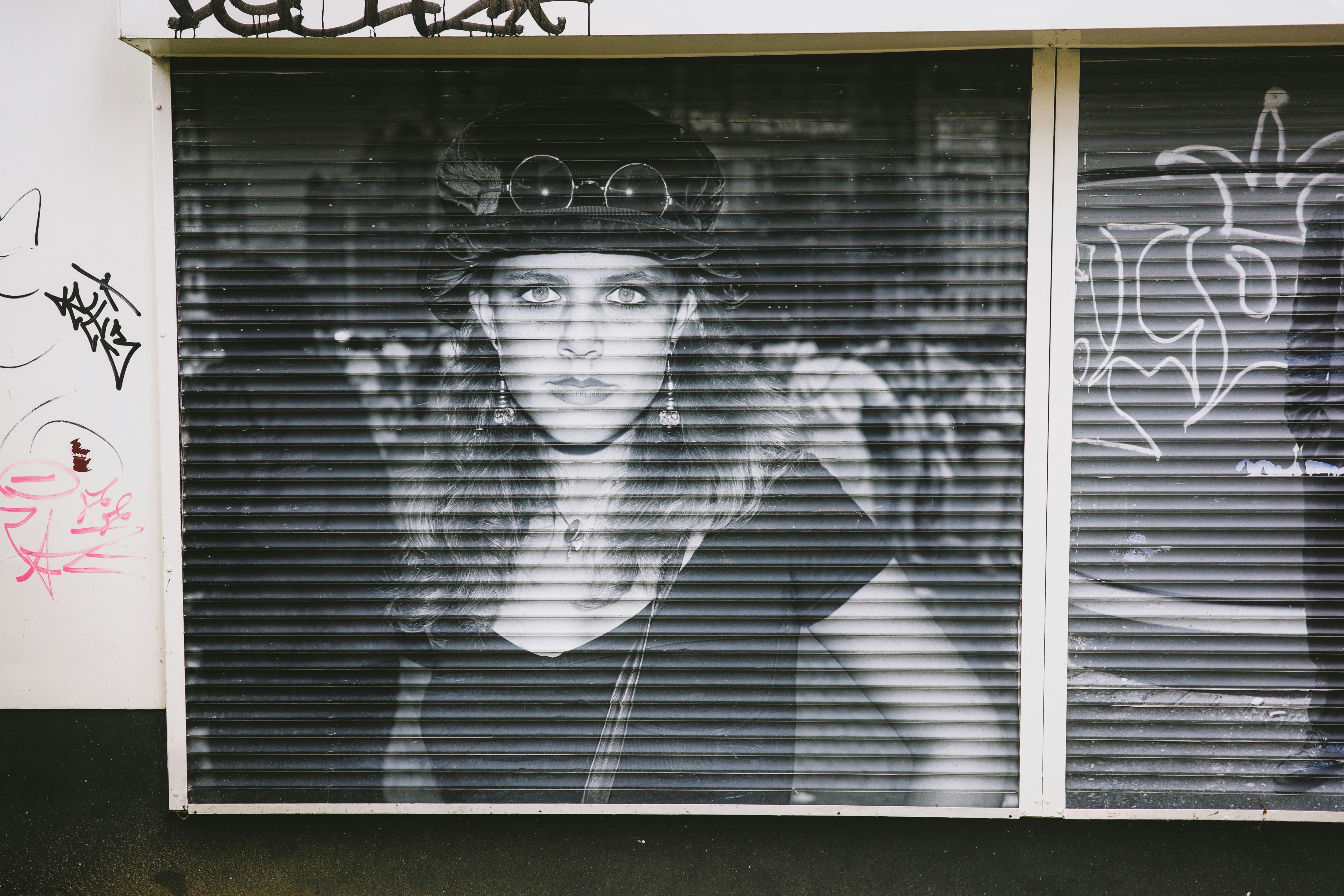 Woman with hat behind closed shutters