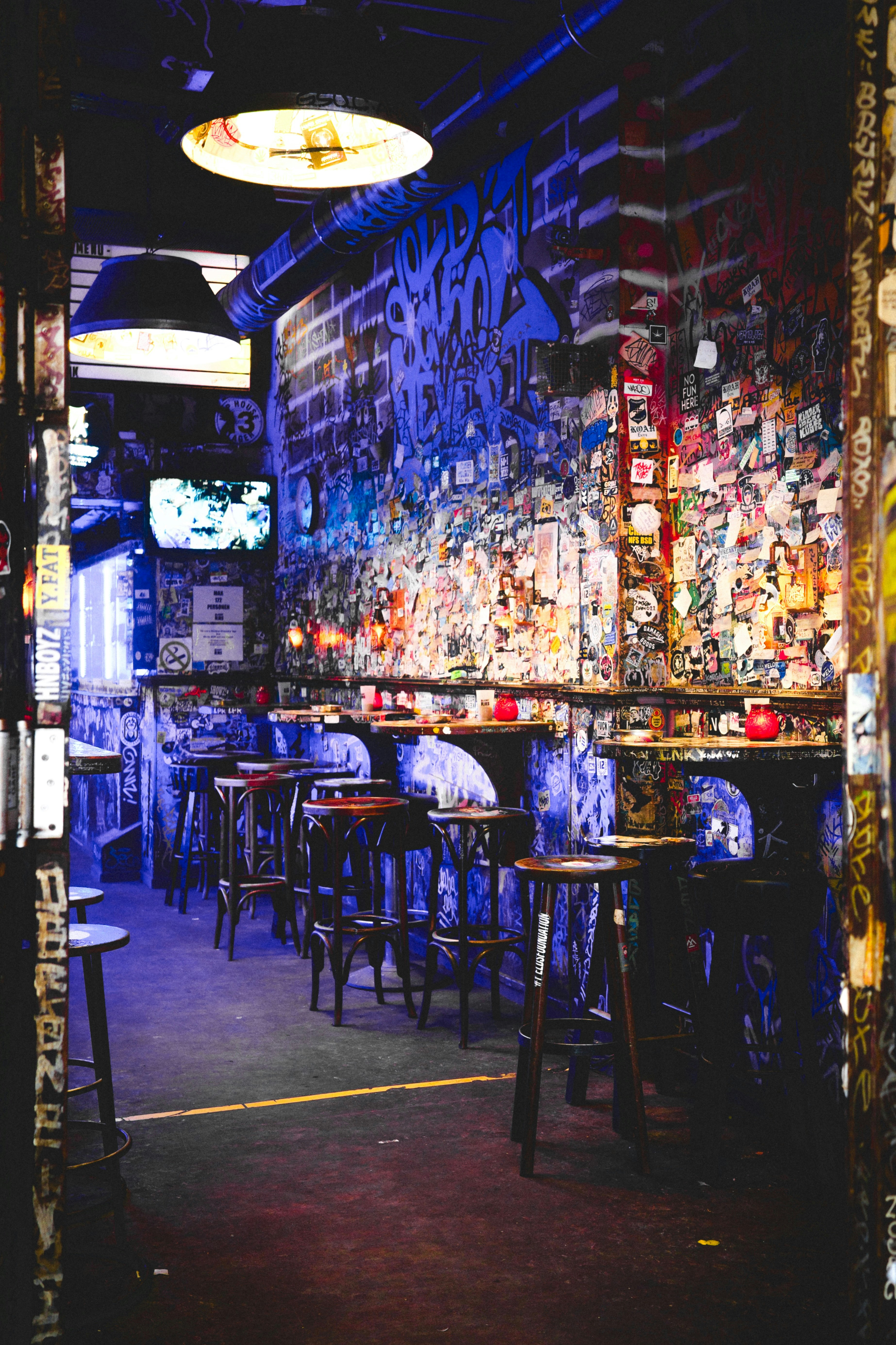 Dimly lit bar with graffiti-covered walls and stools