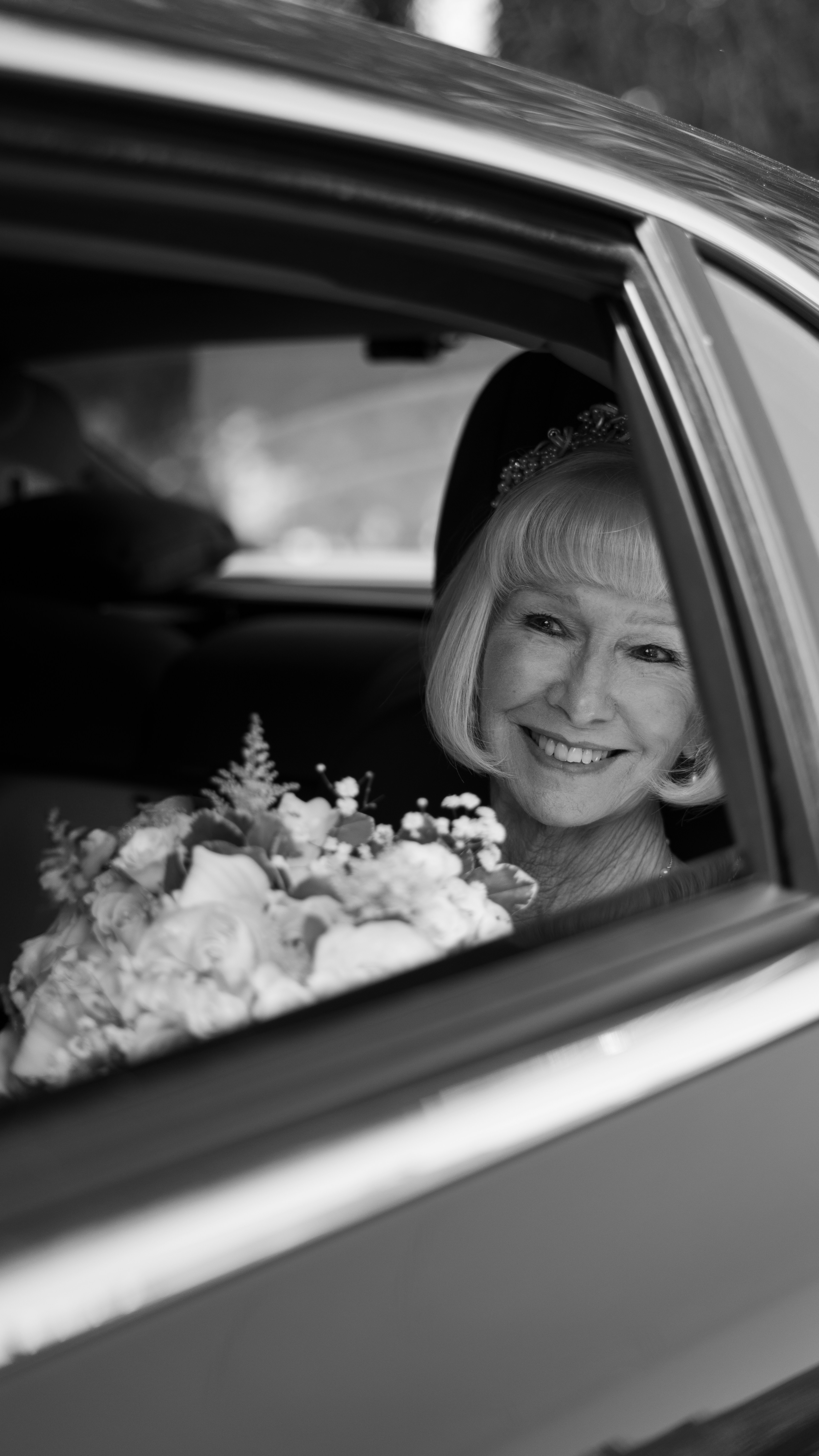 Smiling woman in car with bouquet