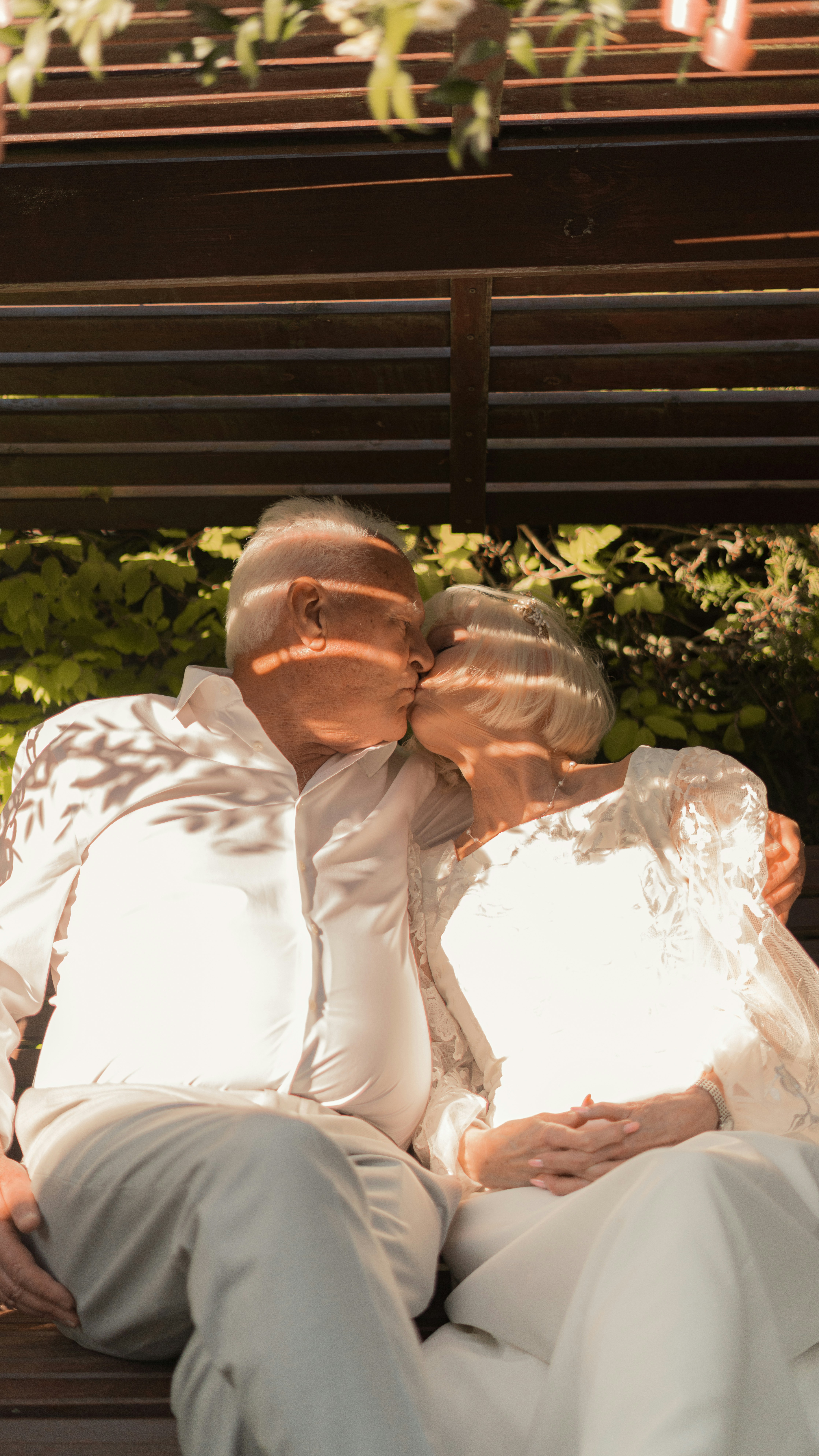 Elderly couple kissing on a park bench