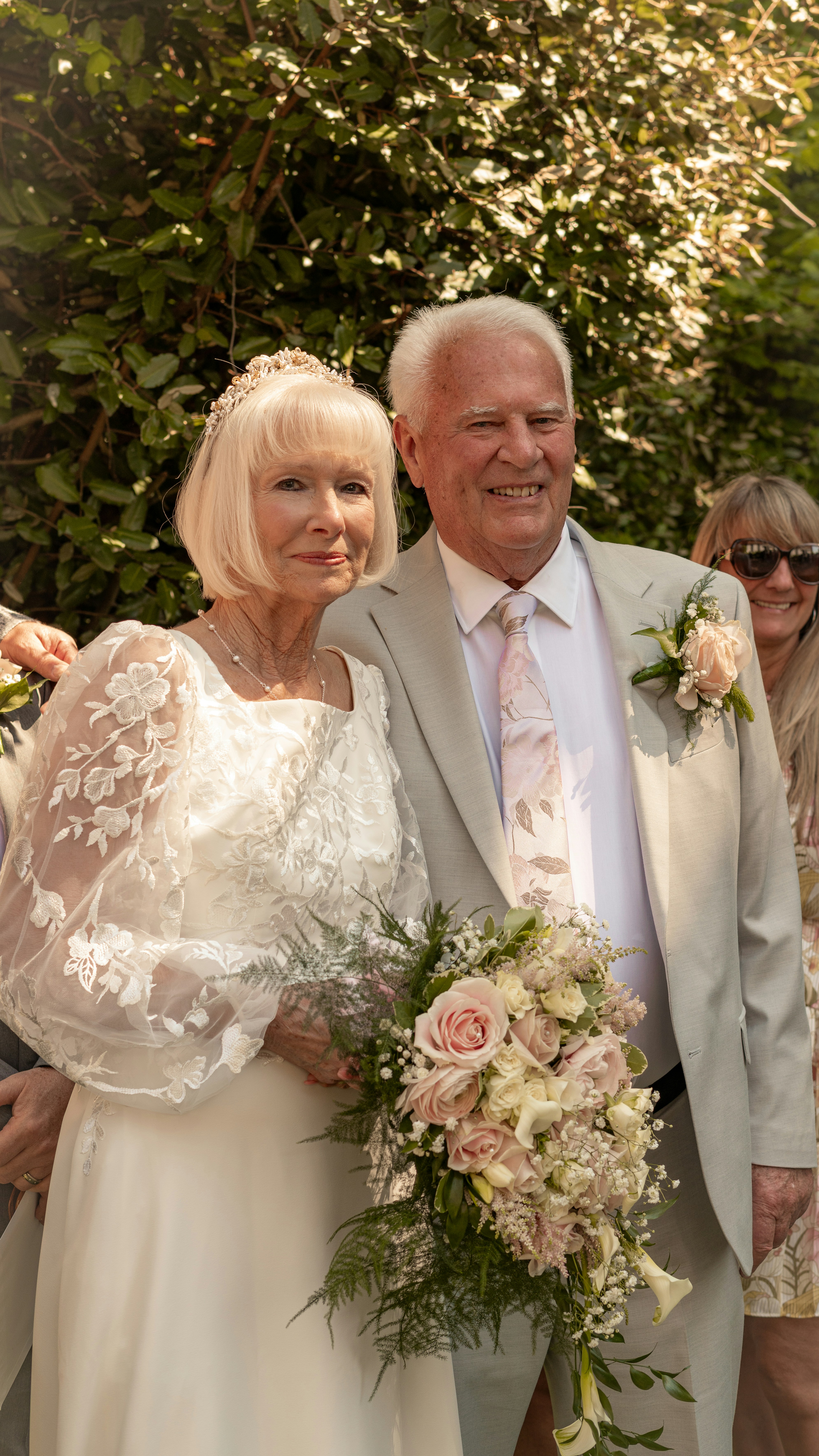 Elderly couple in wedding attire with a bouquet.