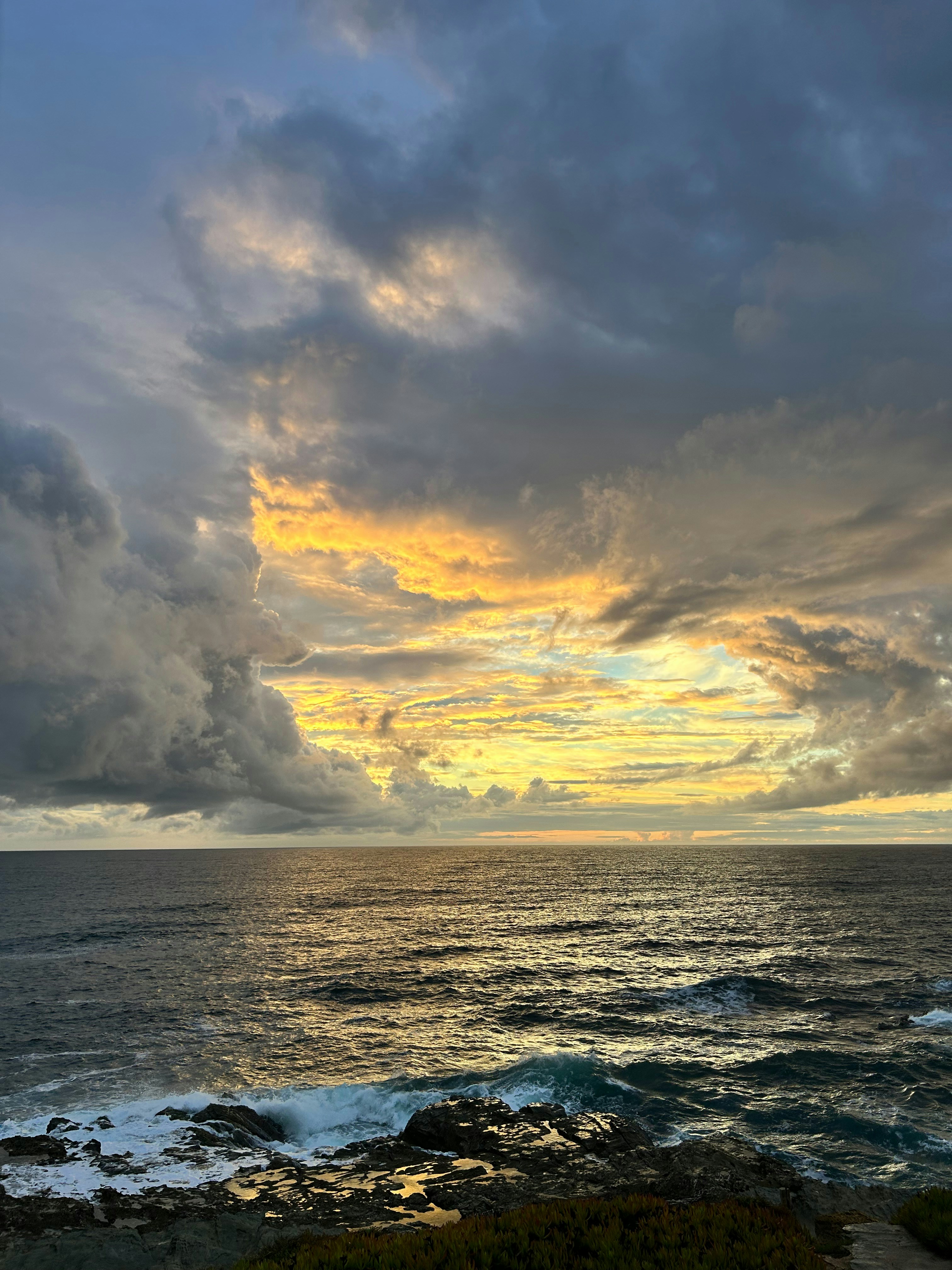 Dramatic sunset over the ocean with crashing waves.