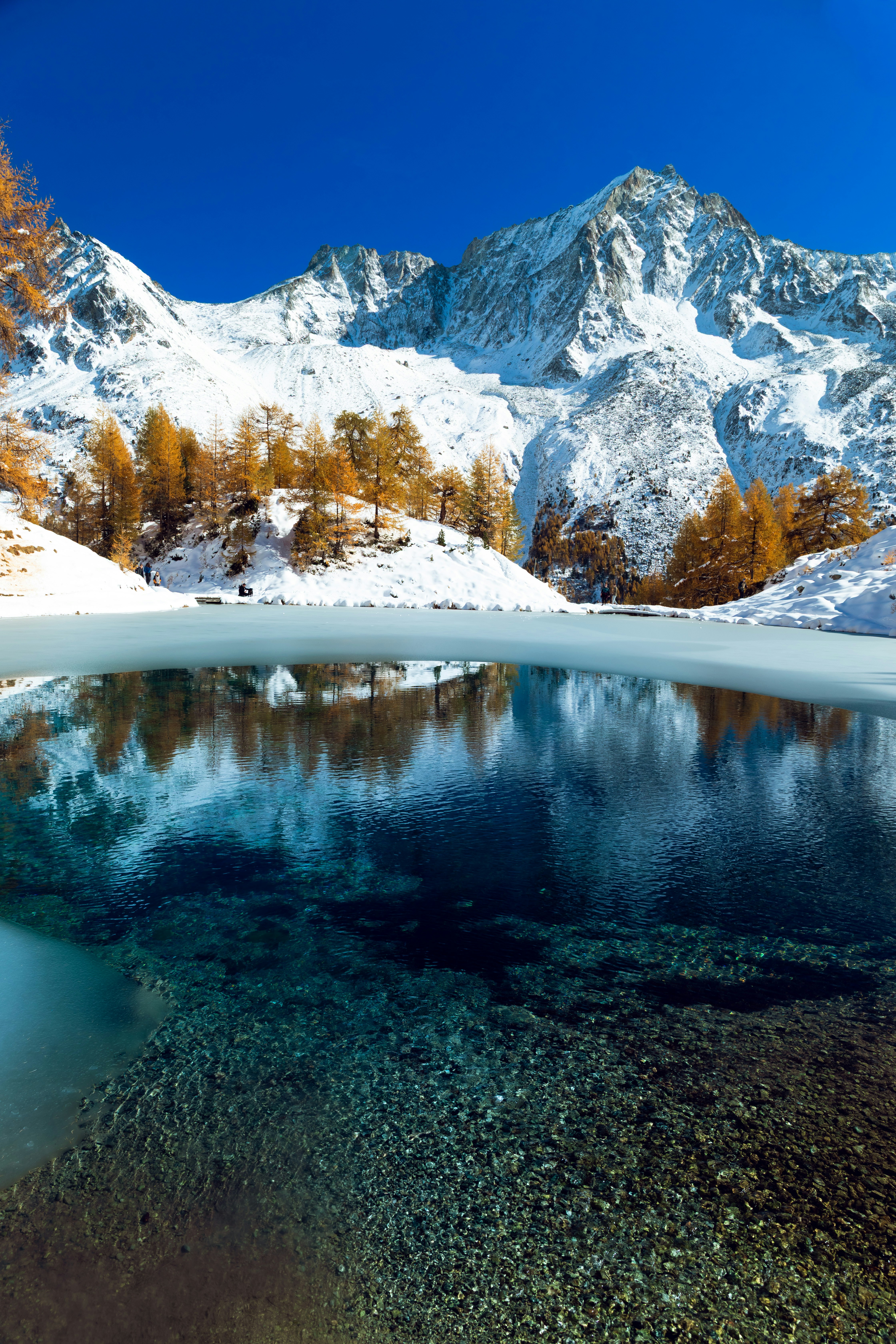 Snow-covered mountains reflected in a clear lake.