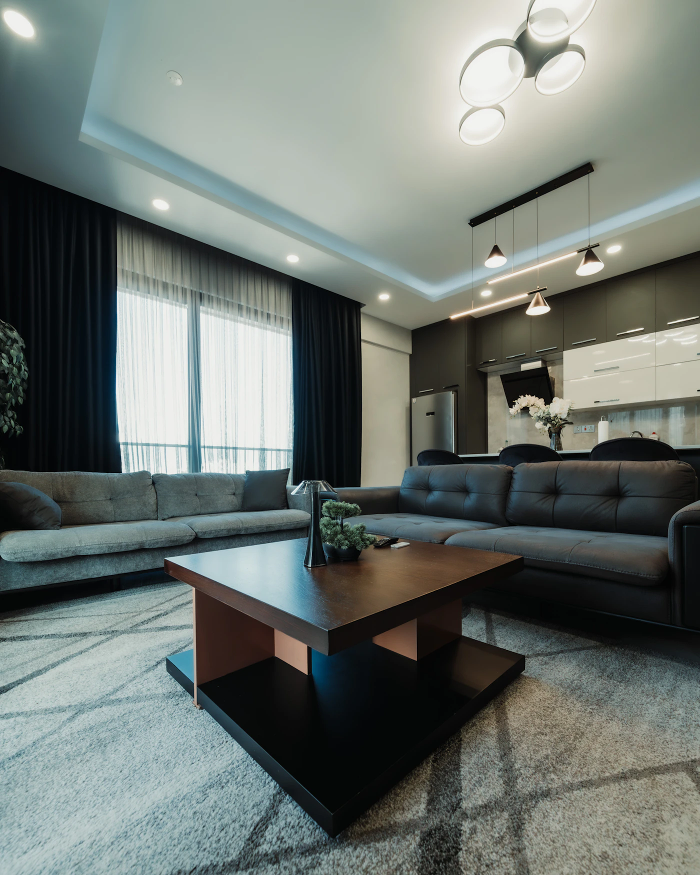 Modern living room with a sectional sofa, coffee table, rug, and soft neutral furnishings