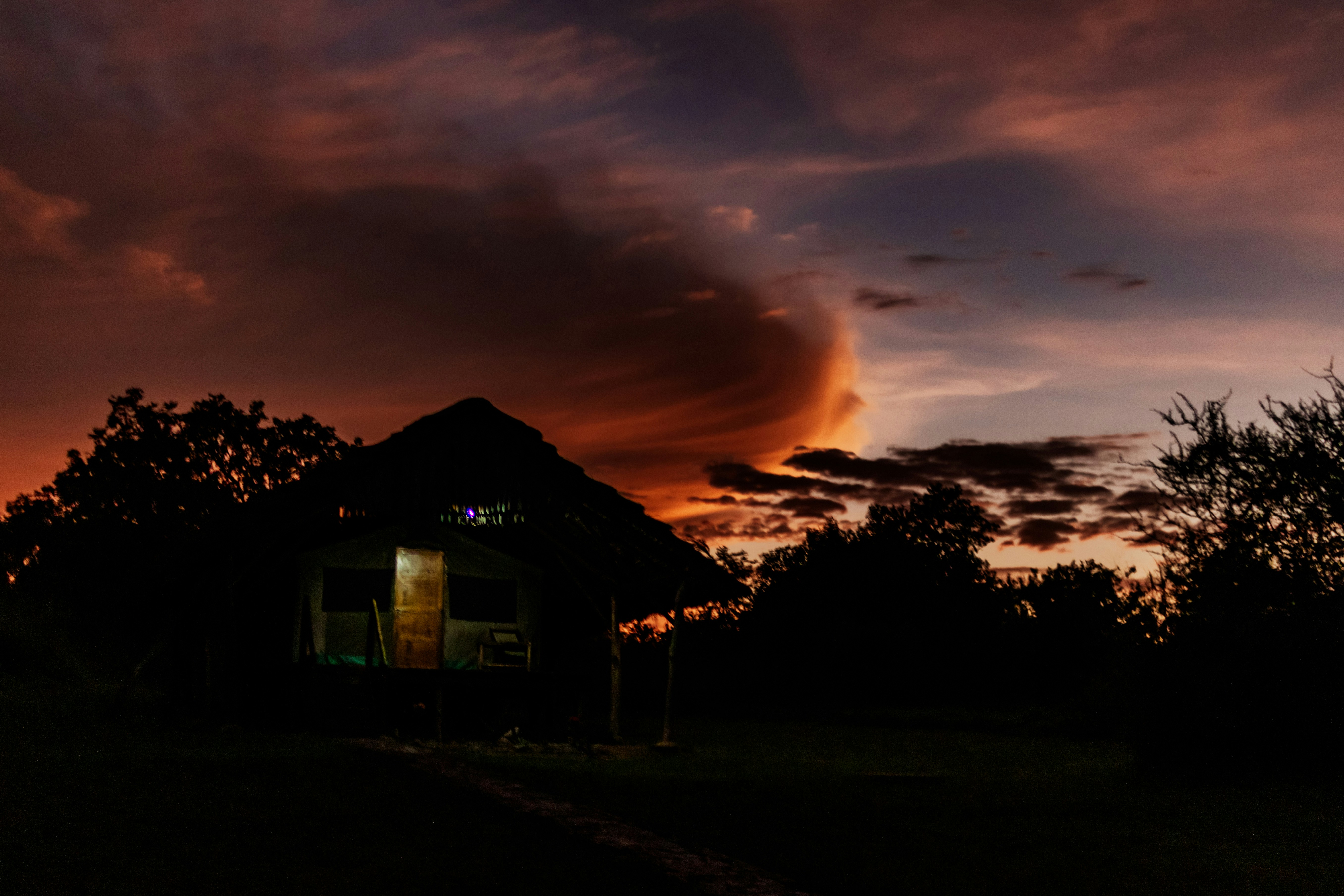 Silhouette of a hut against a dramatic sunset sky.