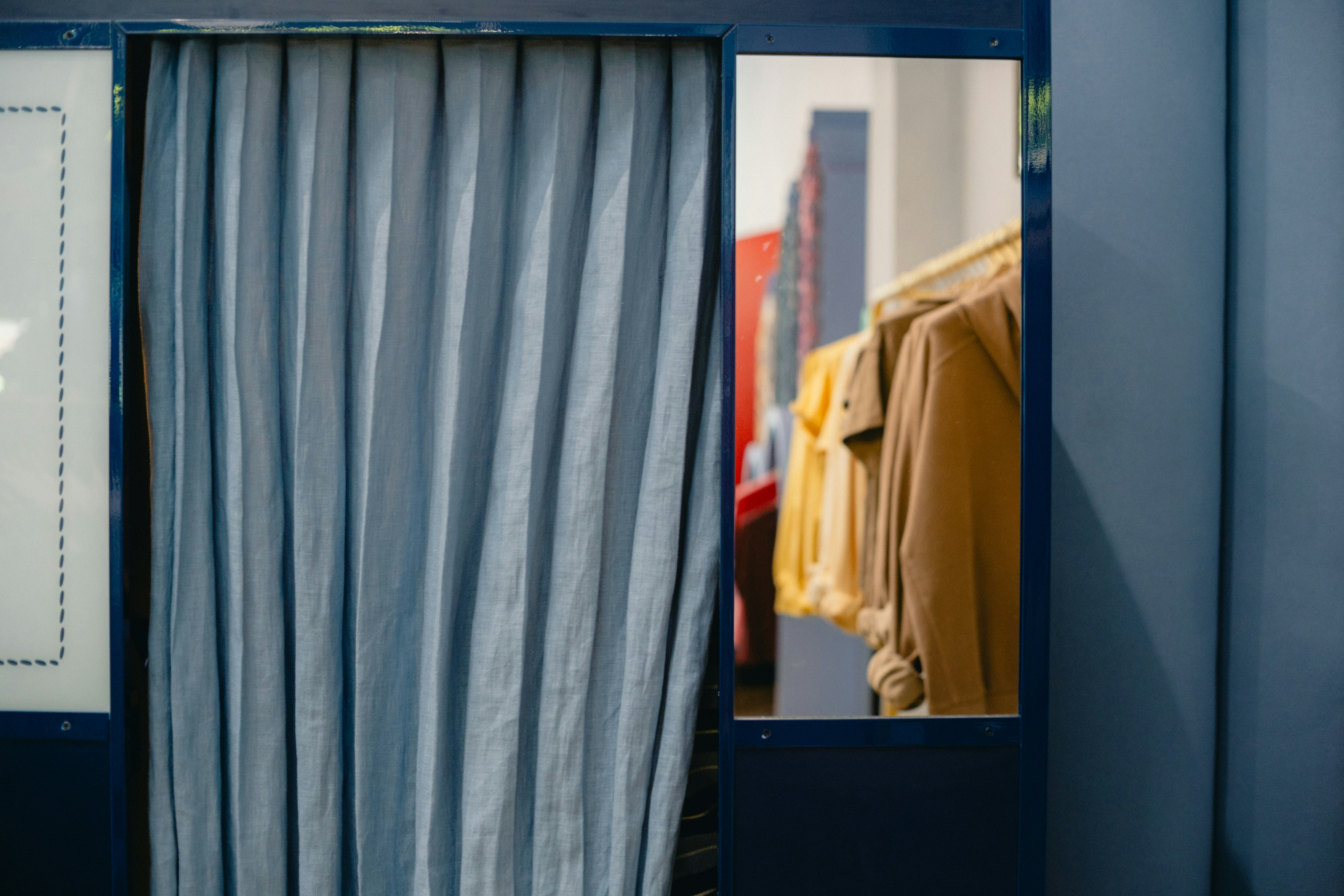 Blue curtain in a changing room with clothes visible