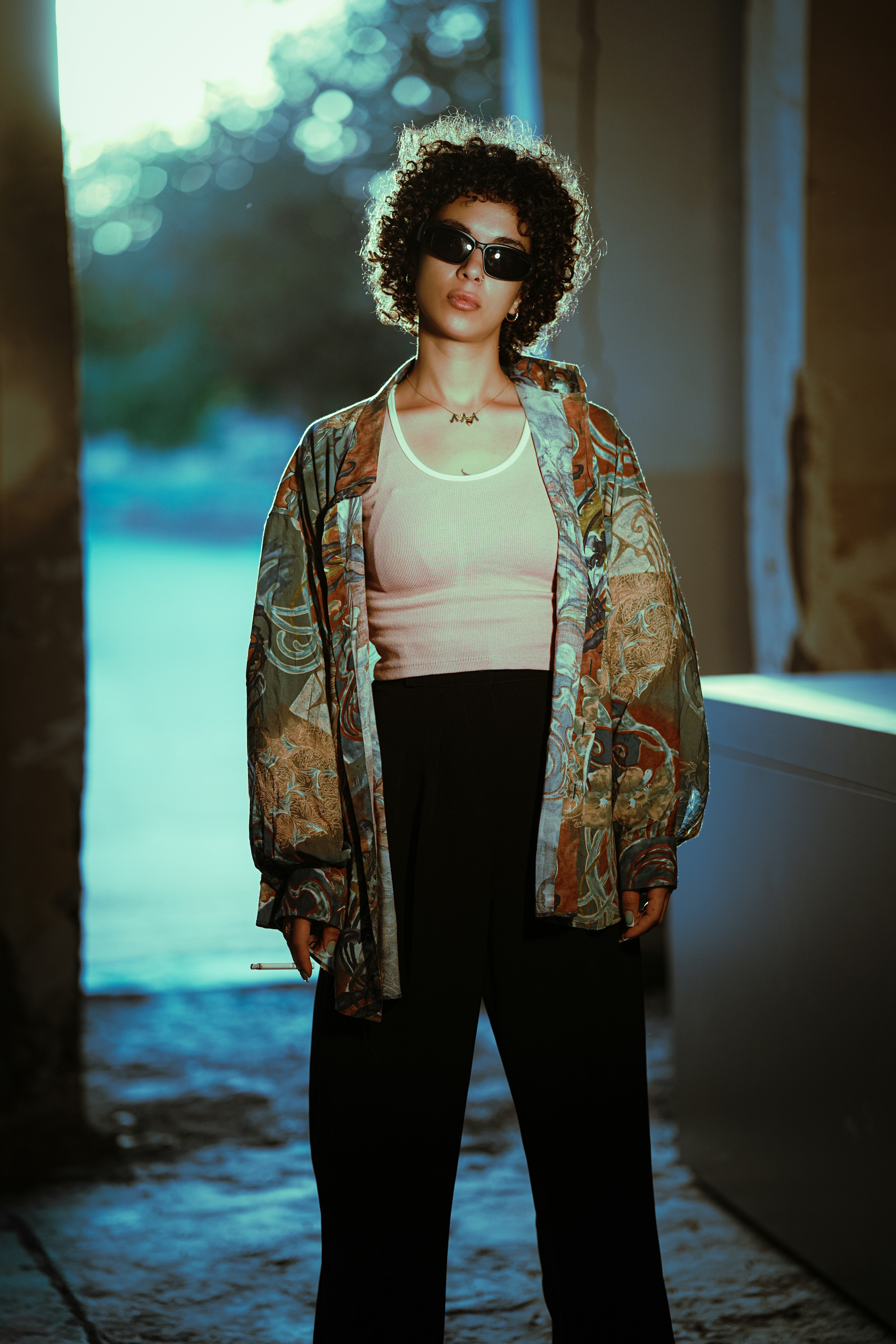 Woman with curly hair wearing sunglasses and patterned jacket