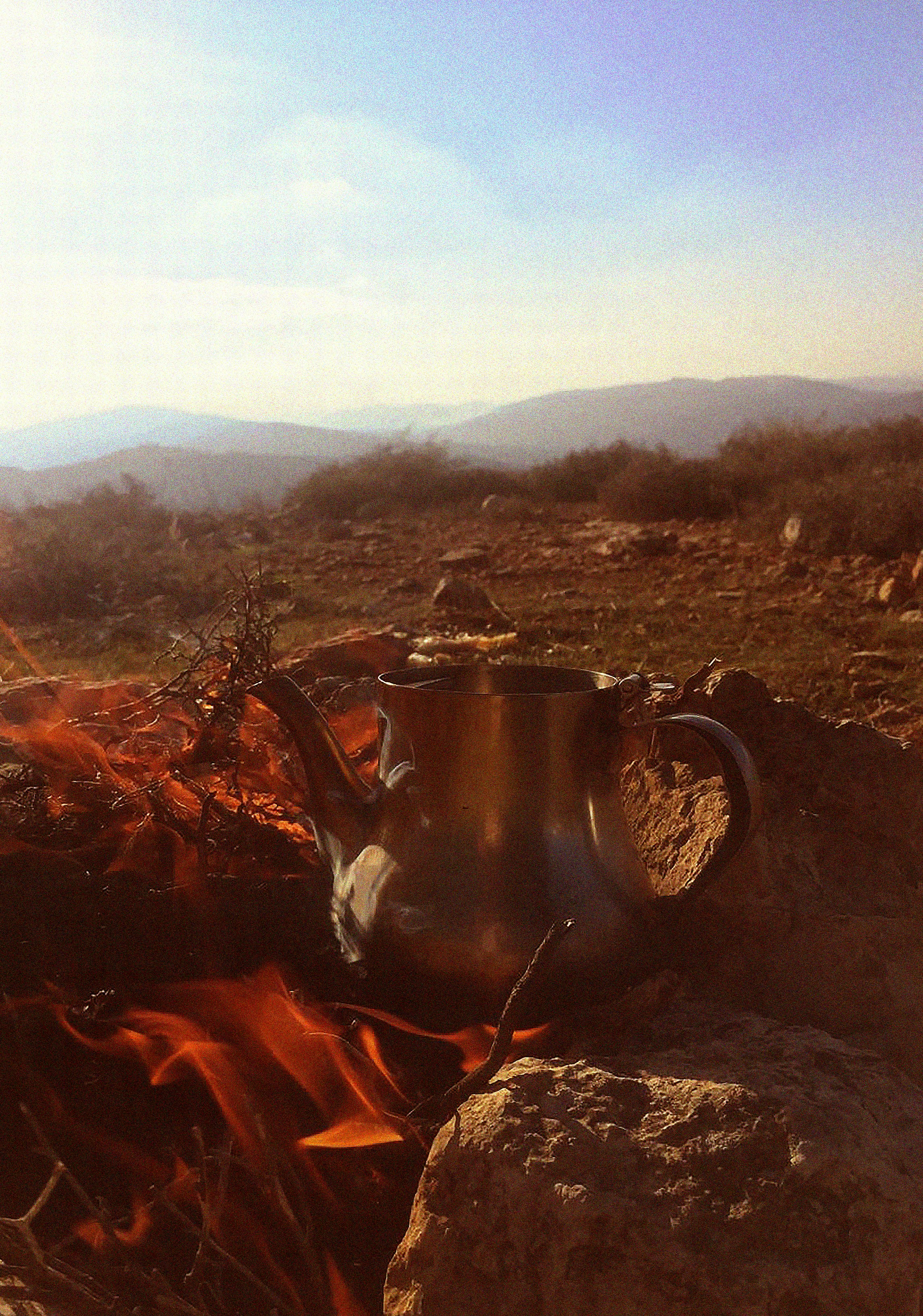 Calentador de tetera sobre una fogata en un paisaje montañoso
