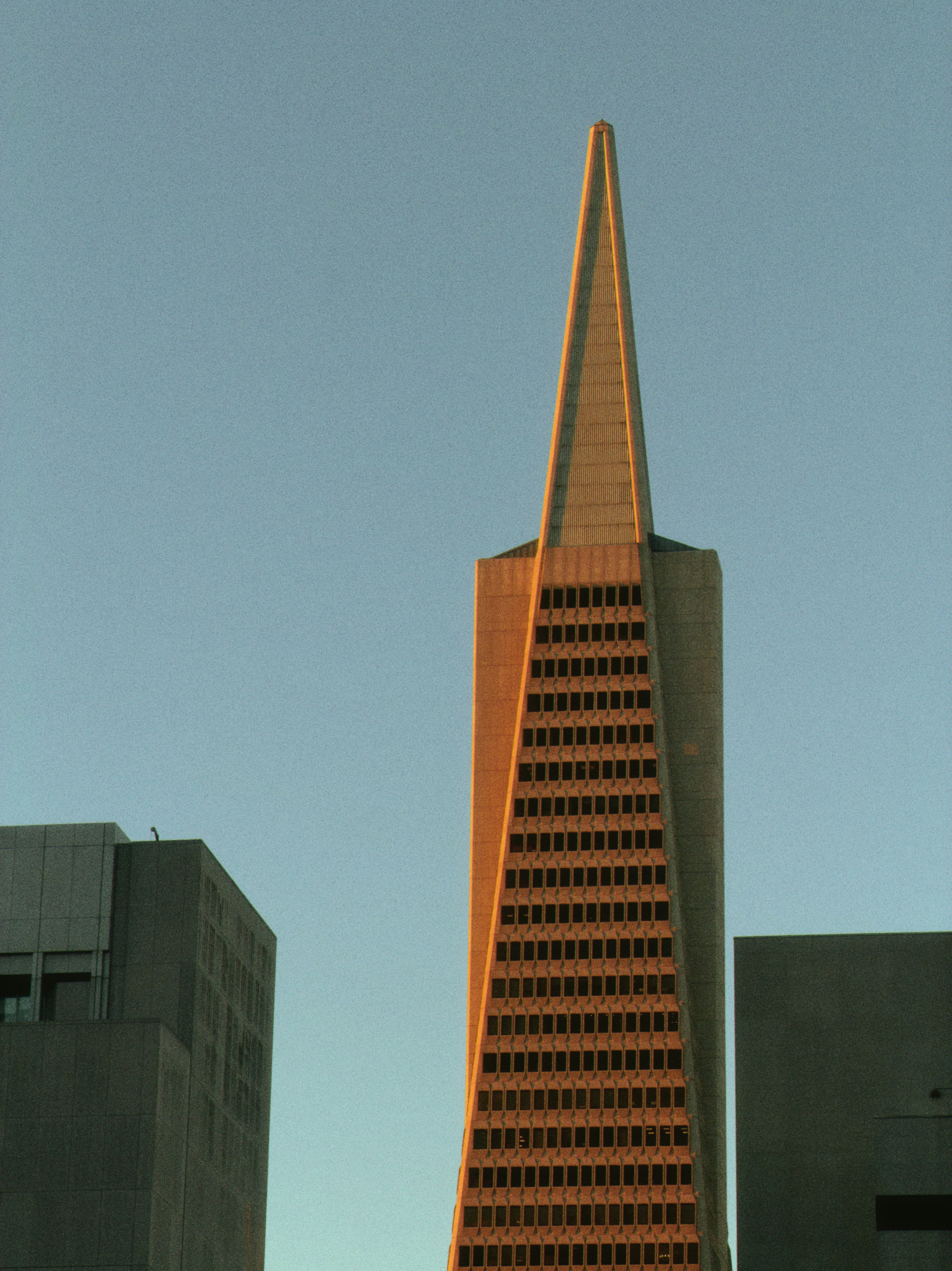 Tall pyramid-shaped skyscraper against a clear blue sky