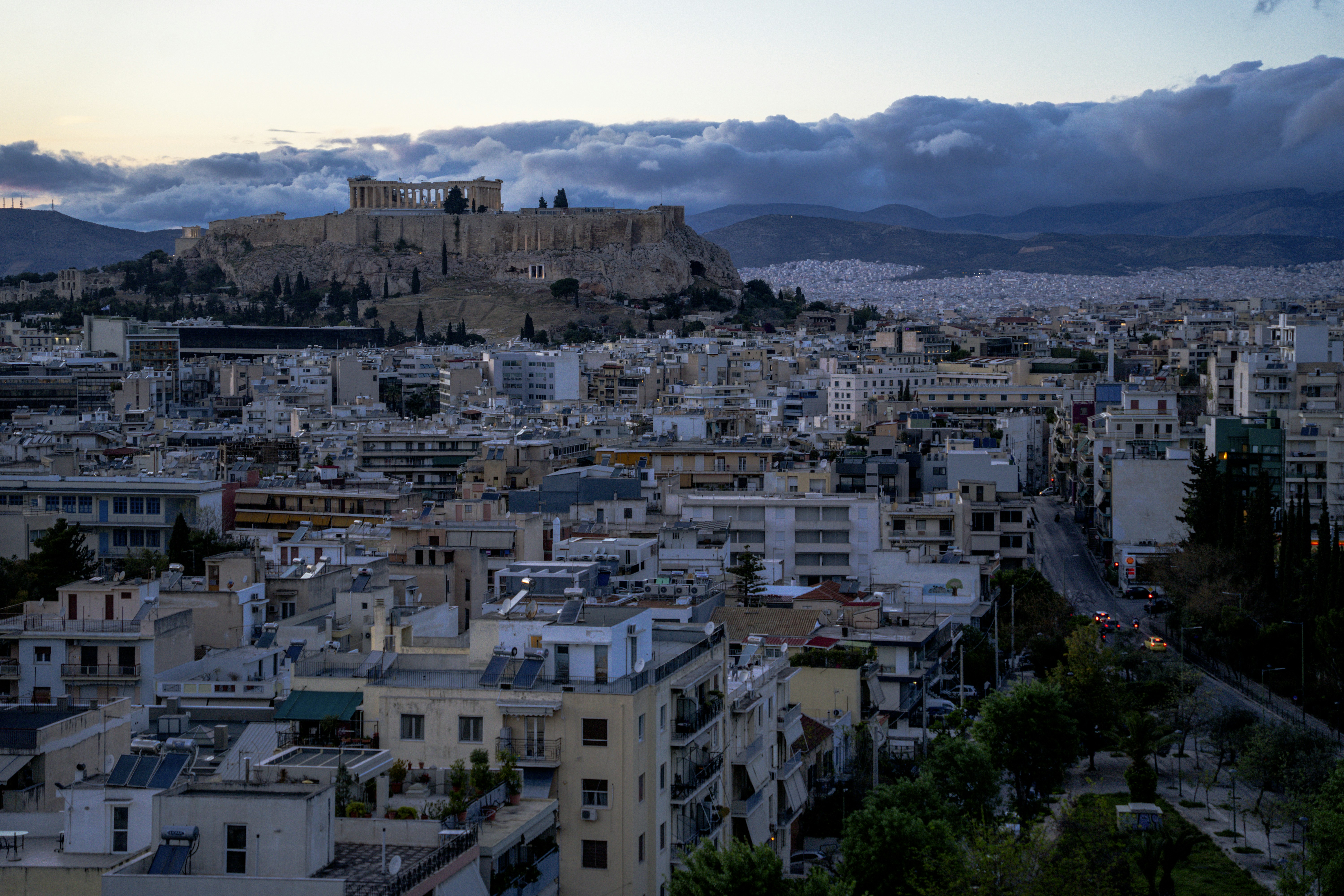 The acropolis of athens overlooking a city at dusk