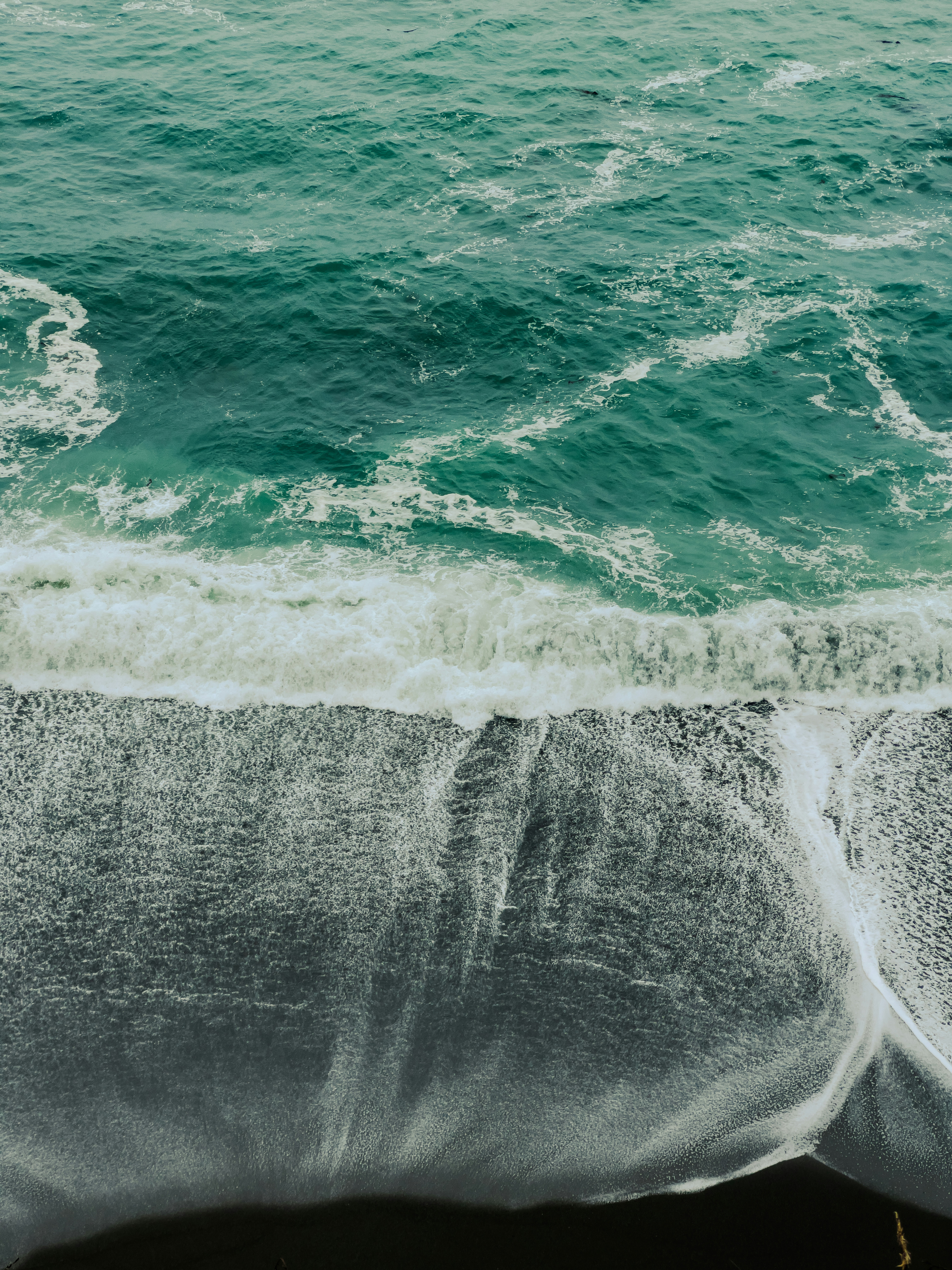 Turquoise waves crash on a dark sandy beach