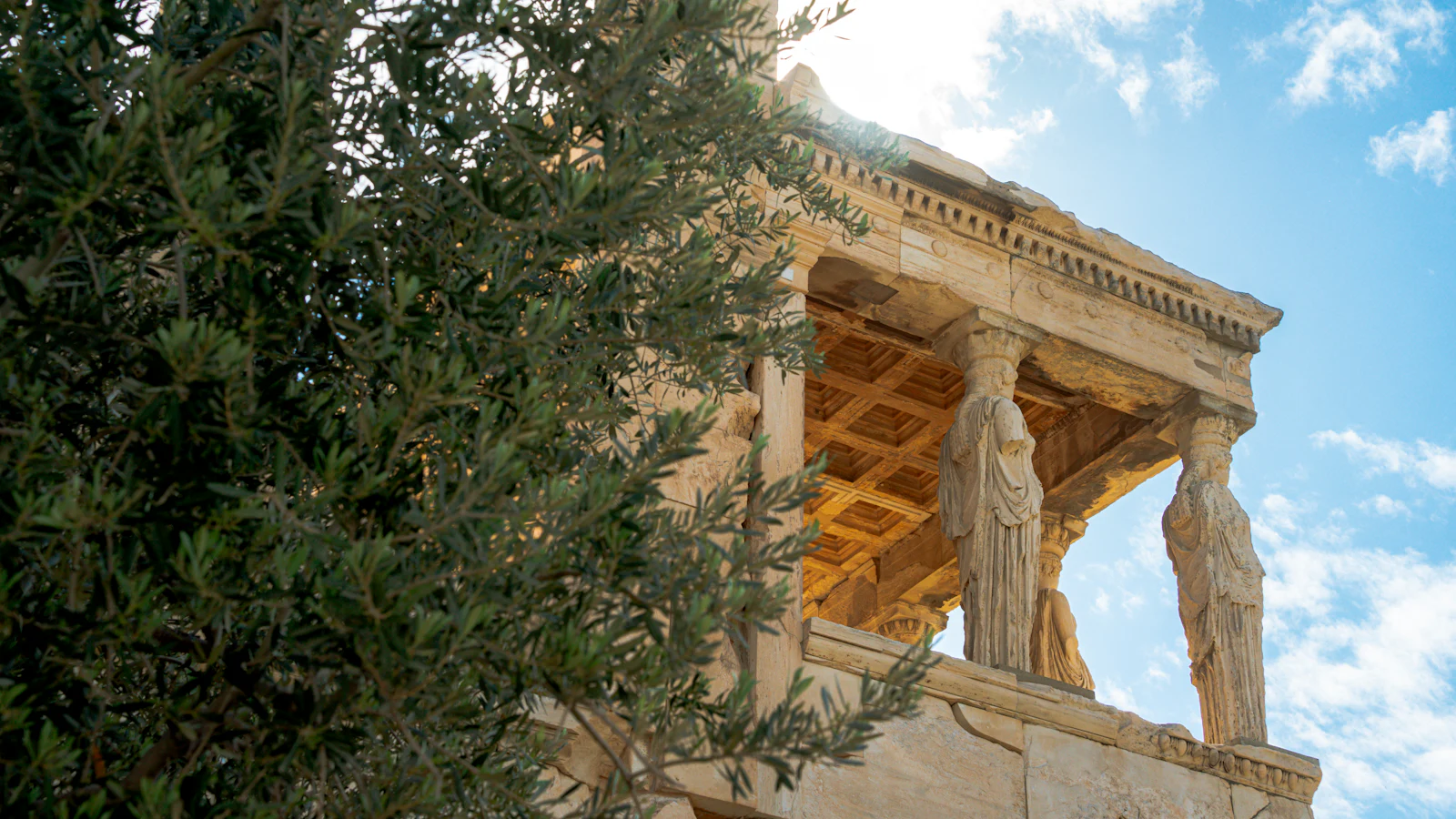 A Greek temple with caryatid columns under a blue sky.